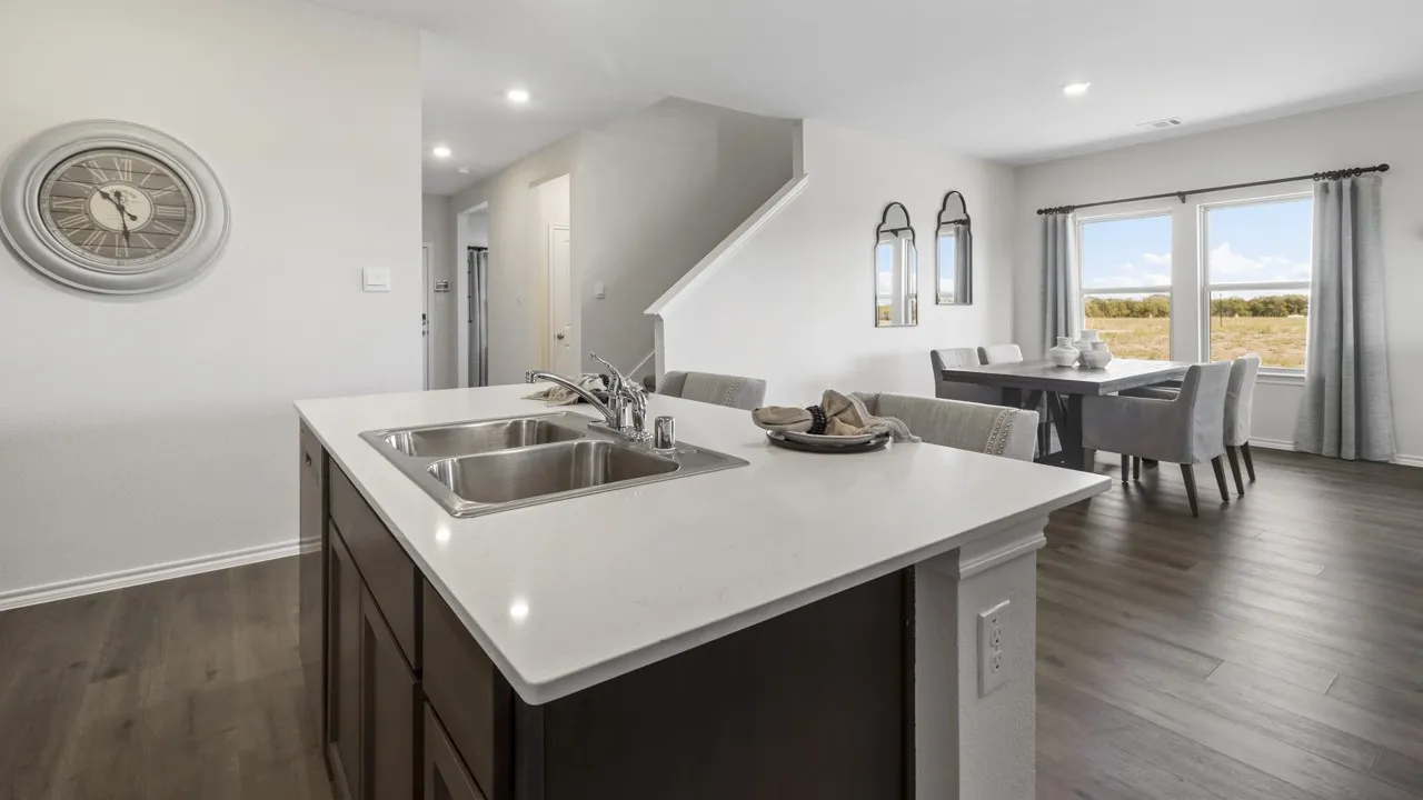 Kitchen island featuring a double-basin stainless steel sink with a chrome faucet, white countertop, and dark wood-finish cabinetry