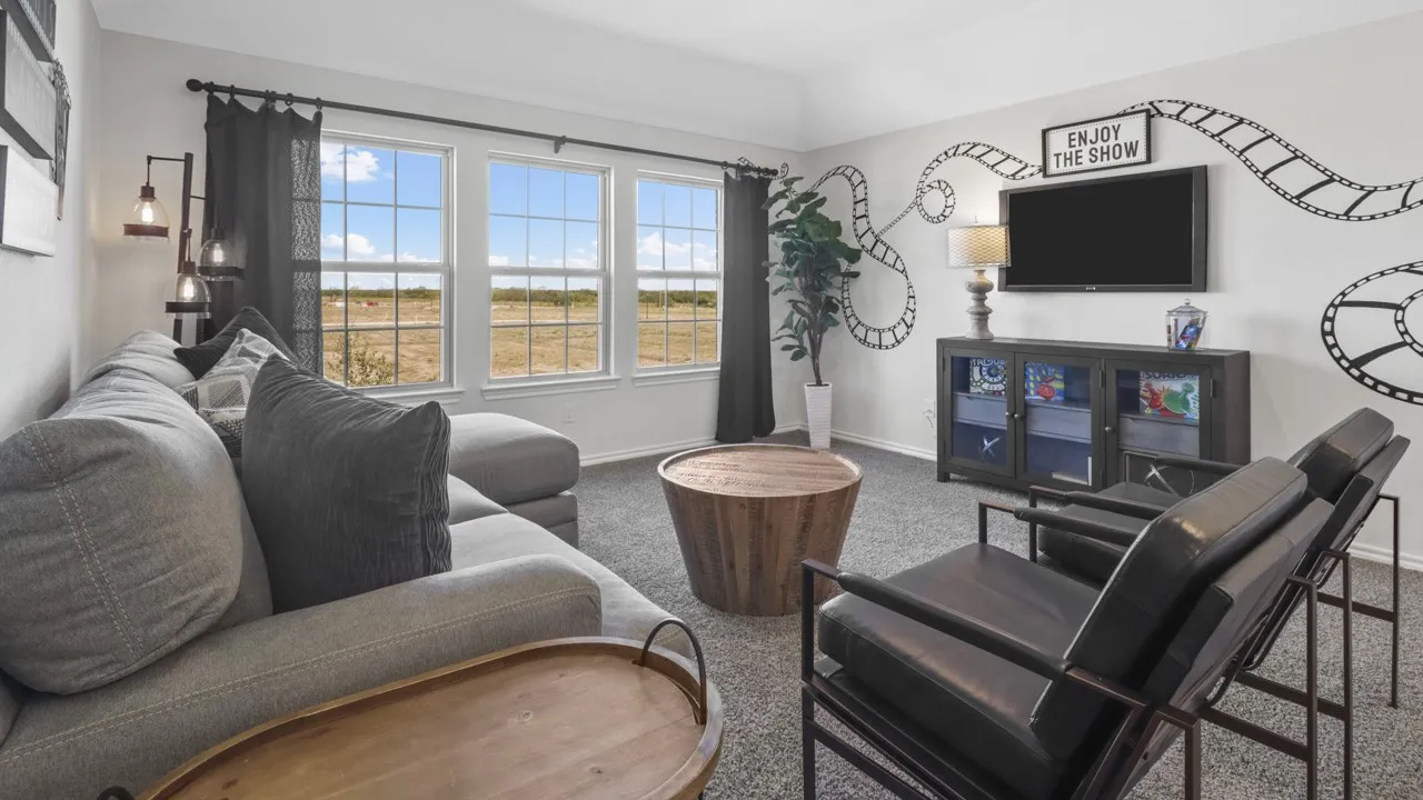 Spacious entertainment room featuring three large windows, textured carpeting, and a built-in media console
