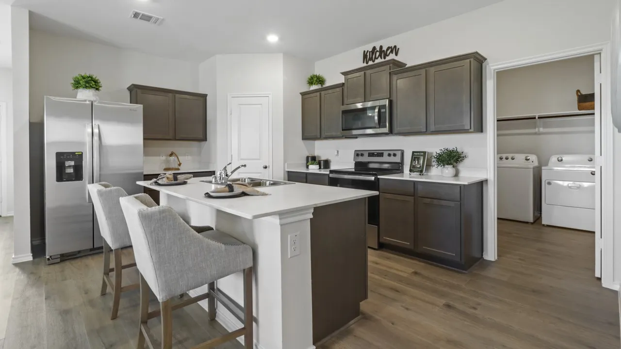 Open-concept kitchen featuring an island with seating, stainless steel appliances, dark wood-finish cabinetry, light countertops, and wood-finish flooring