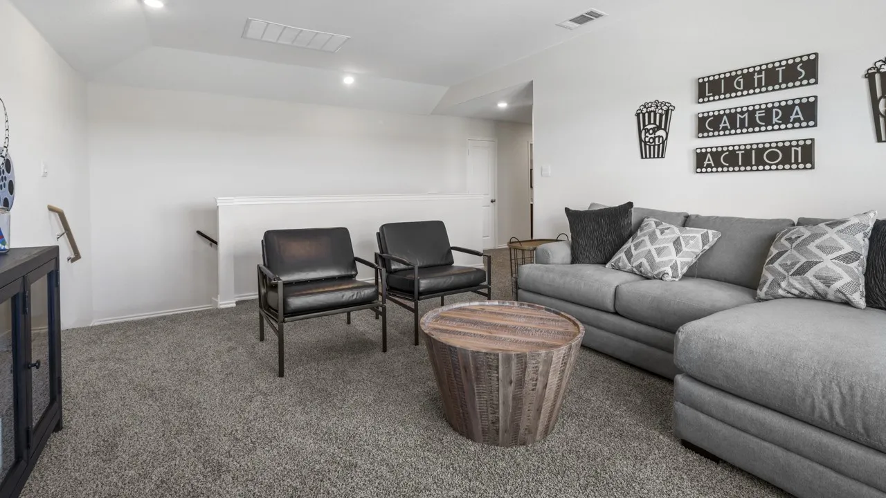 Carpeted living area featuring recessed lighting, a half-wall partition with a handrail, and a sloped ceiling