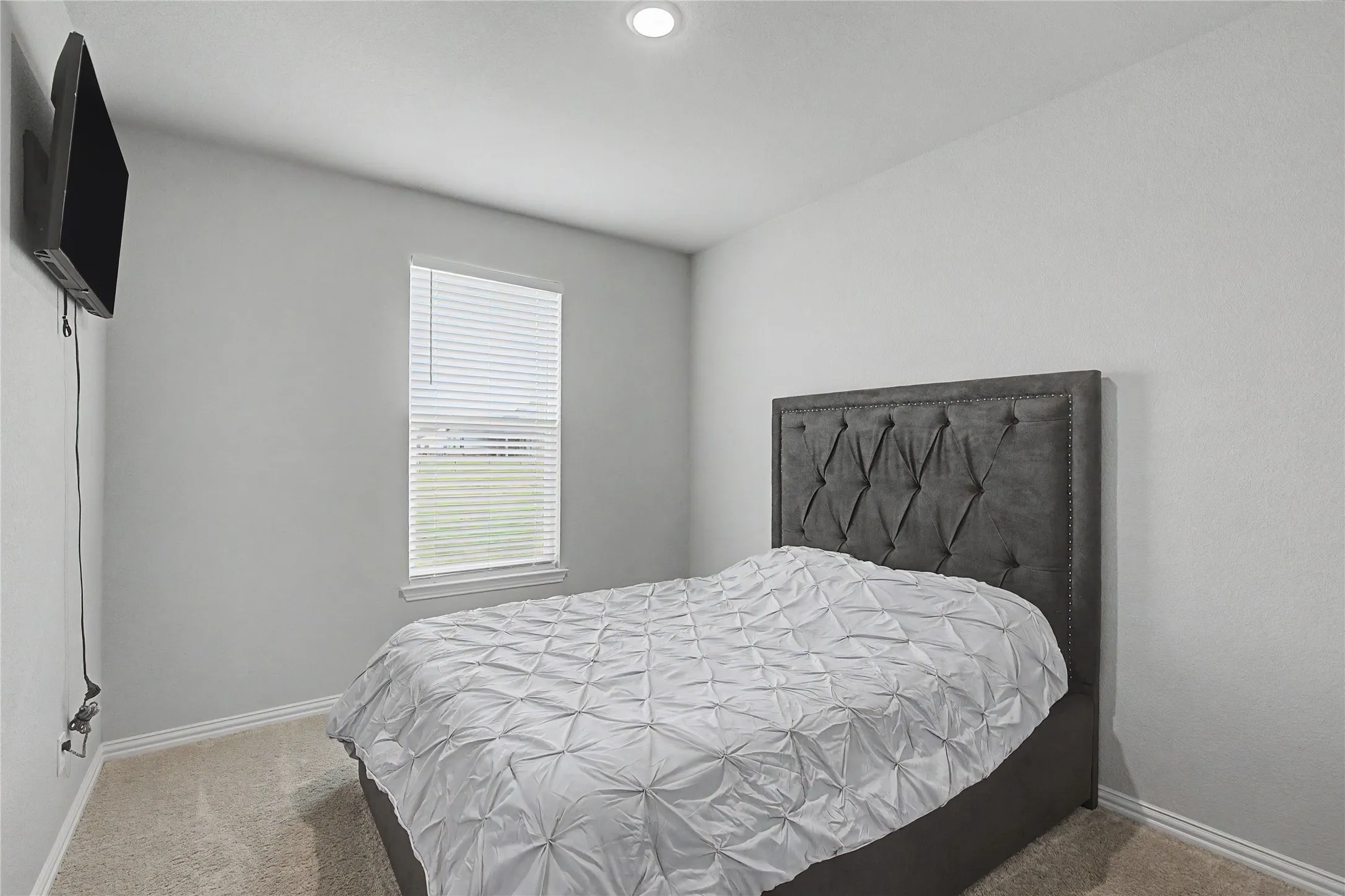 Neutral-toned room featuring a single window with blinds, recessed ceiling lighting, and carpeted flooring