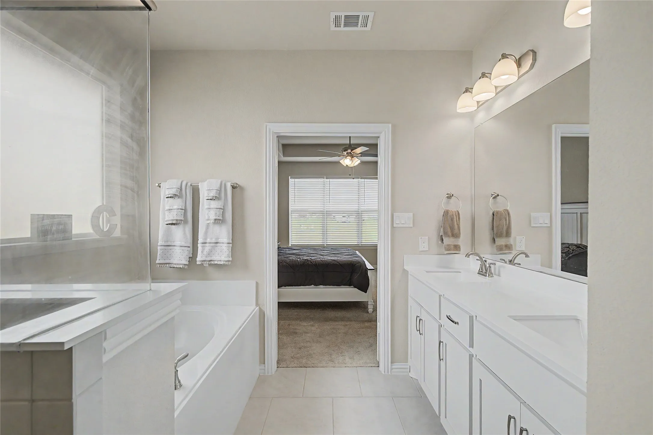 Bathroom featuring a double vanity with white cabinetry, light countertops, and an integrated rectangular sink