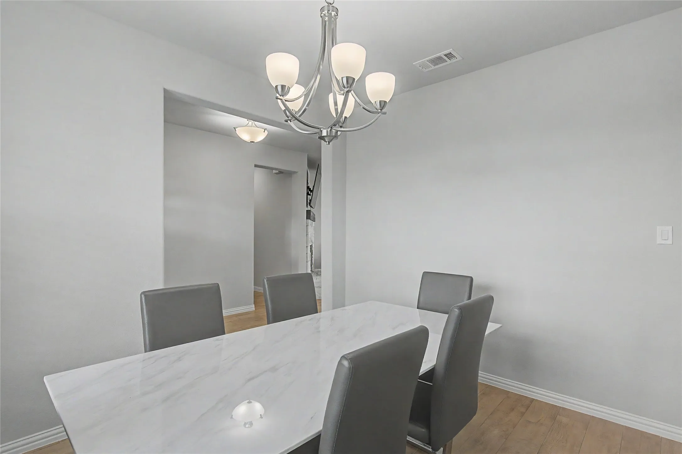 Dining area featuring wood-finish flooring, a contemporary chandelier, and recessed lighting in the hallway