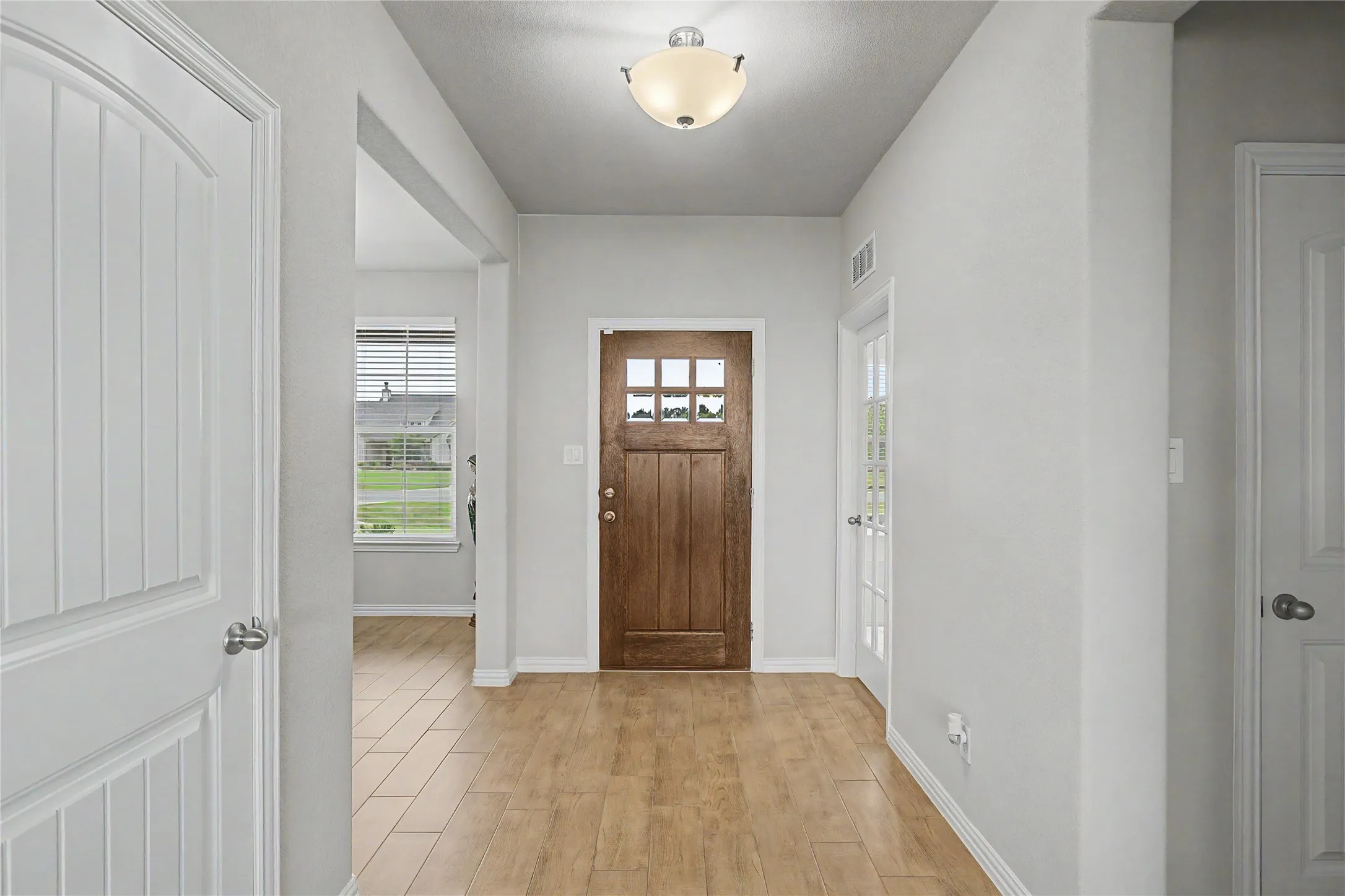 Entryway featuring wood-finish flooring, a six-paneled wood entry door, and a semi-flush mount ceiling light