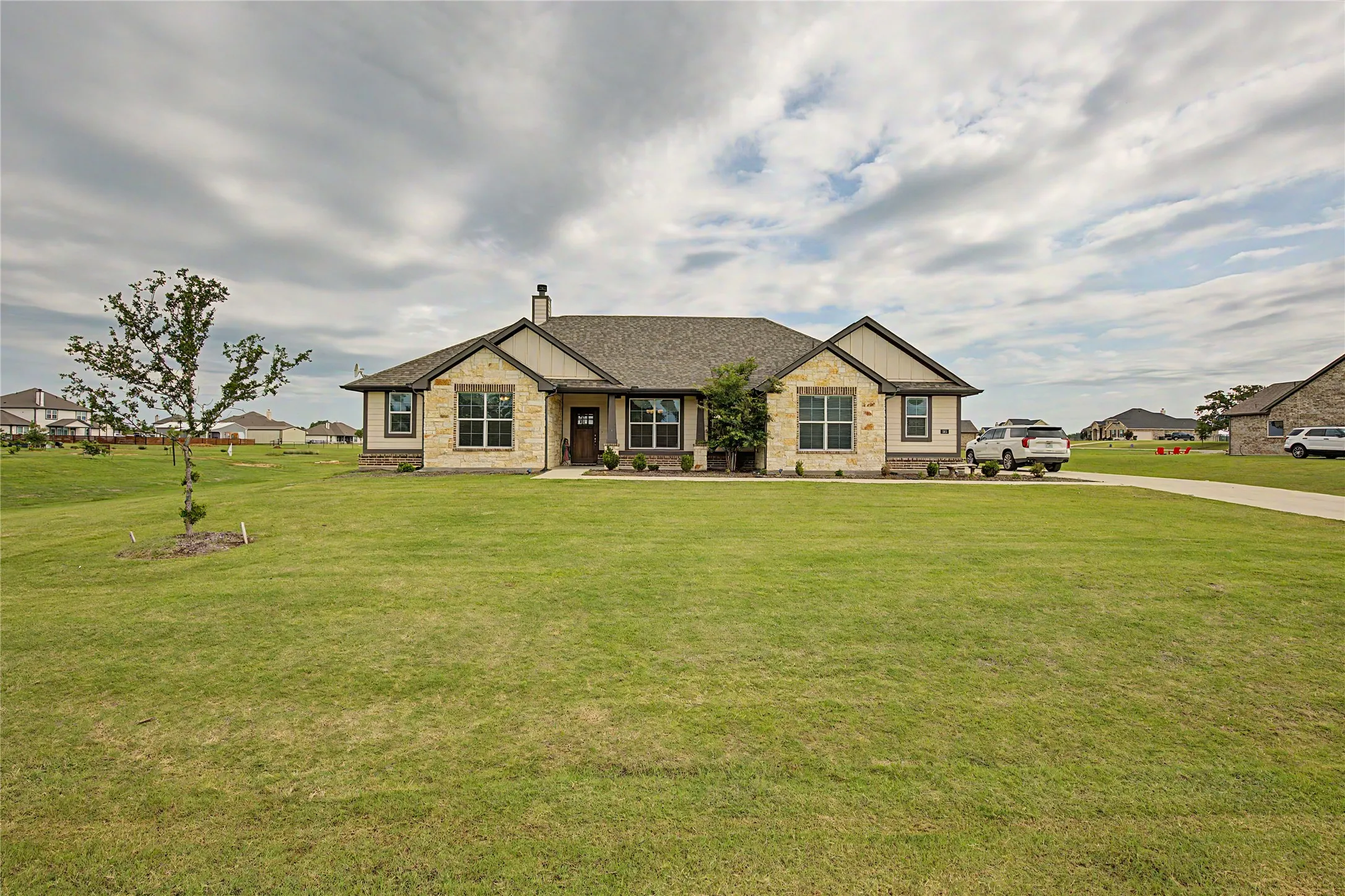 Ranch-style residence featuring a stone and siding facade, a gabled roofline, and a prominent front entry