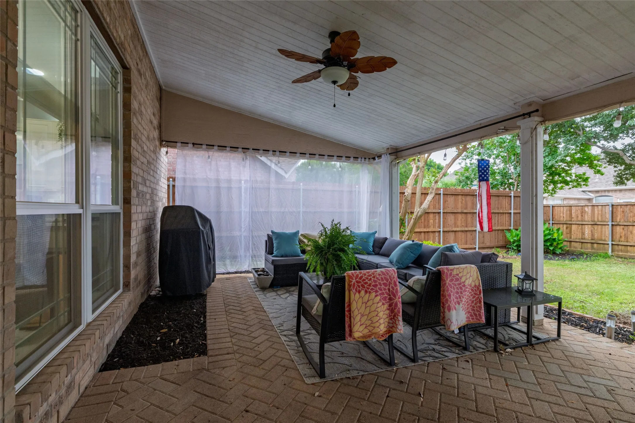 Covered patio featuring a slatted wood ceiling with a ceiling fan