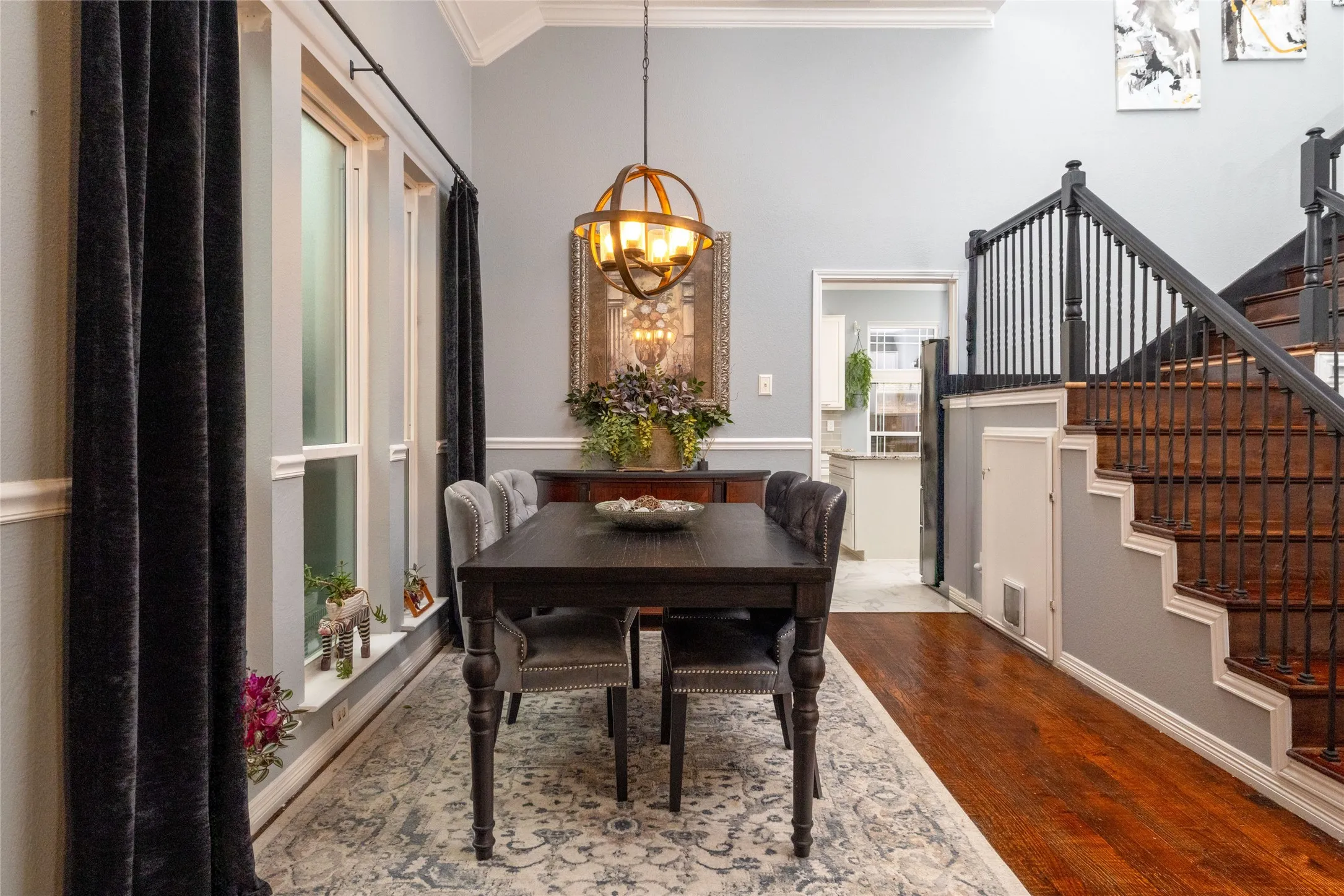Formal dining space featuring wood-finish flooring, high ceilings with crown molding, and a staircase with wrought iron balusters