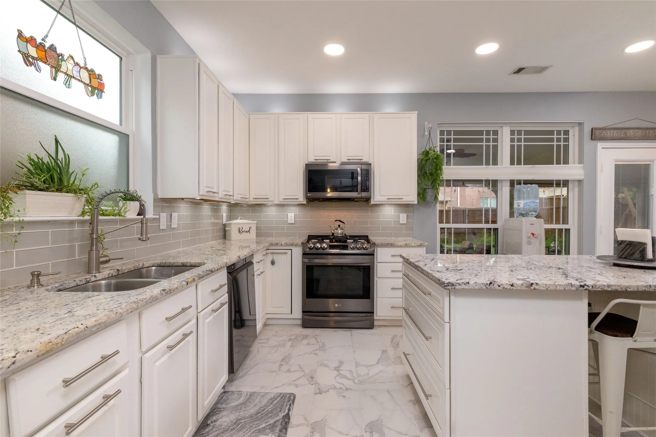 Kitchen with white cabinetry, granite countertops, and a subway tile backsplash