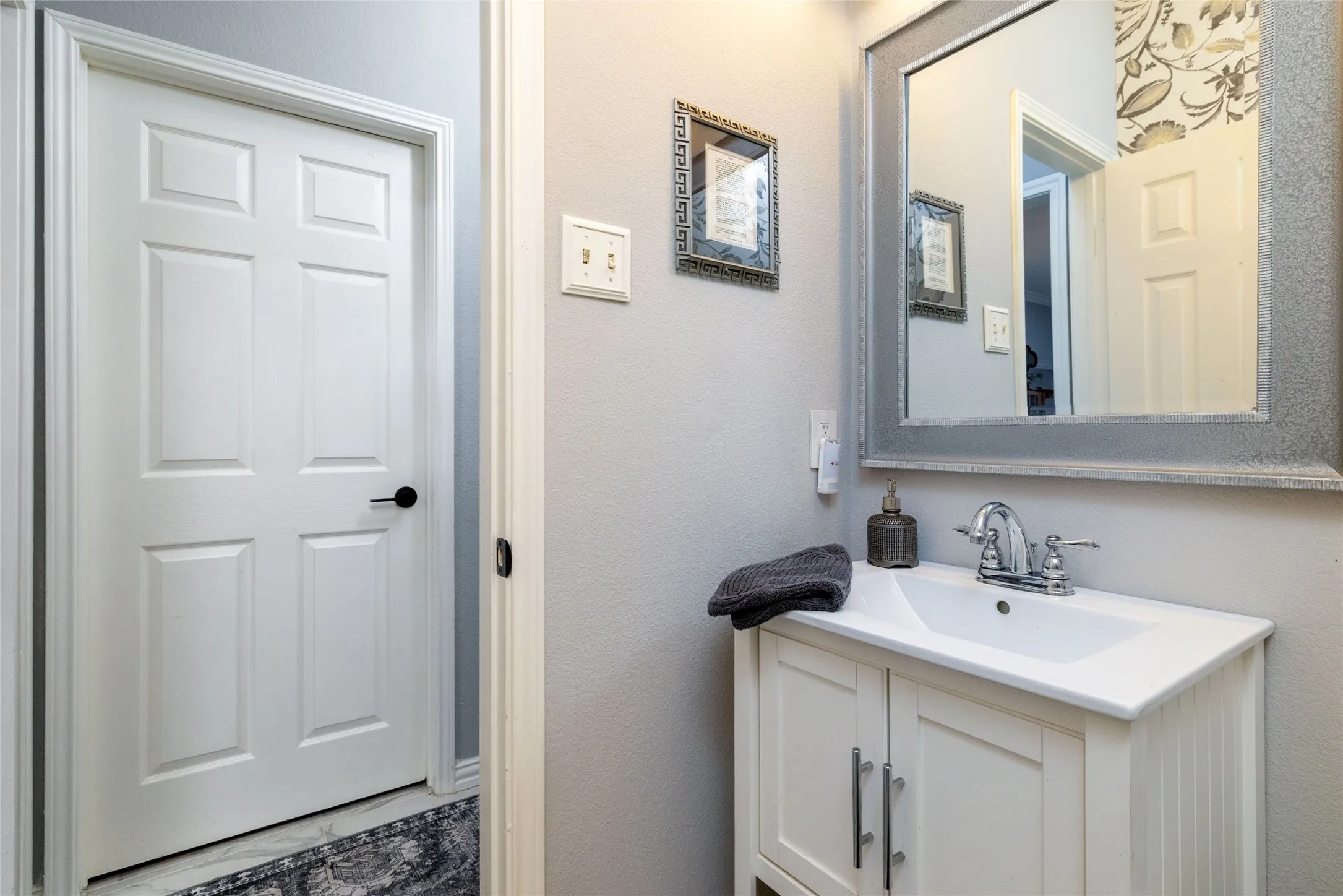White vanity with integrated sink, chrome faucet, and framed mirror