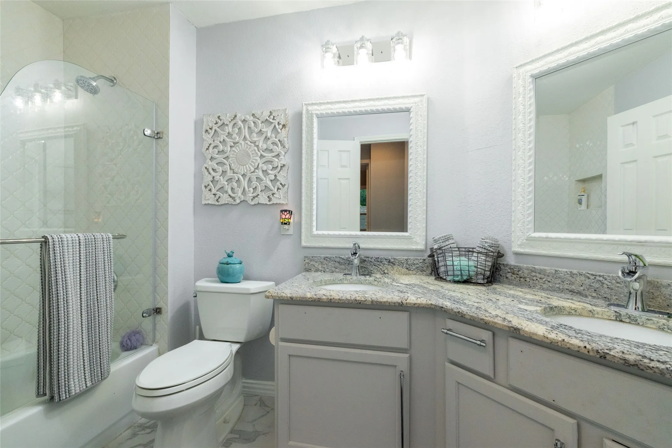 Bathroom featuring a dual vanity with light gray cabinetry, granite countertops, and individual framed mirrors