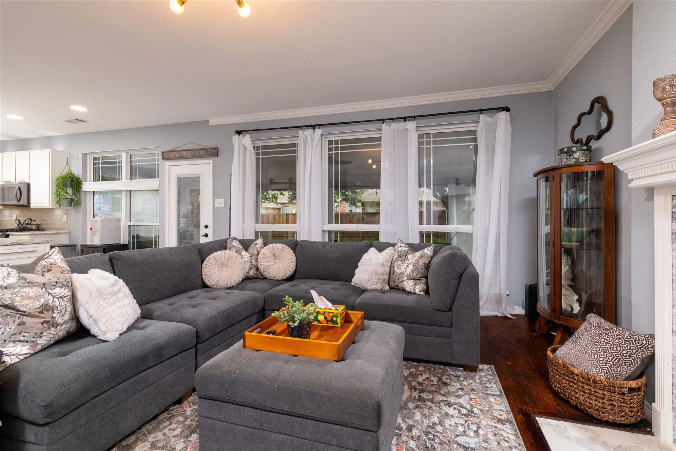 Open-concept living area featuring dark wood-finish flooring, light gray walls, and crown molding