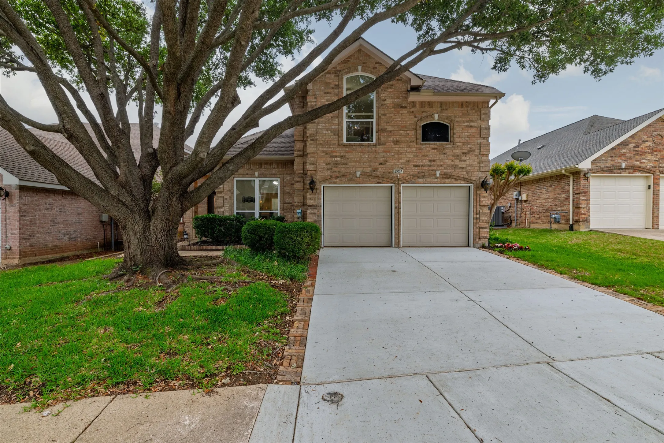 Brick exterior featuring an arched window and a two-car garage