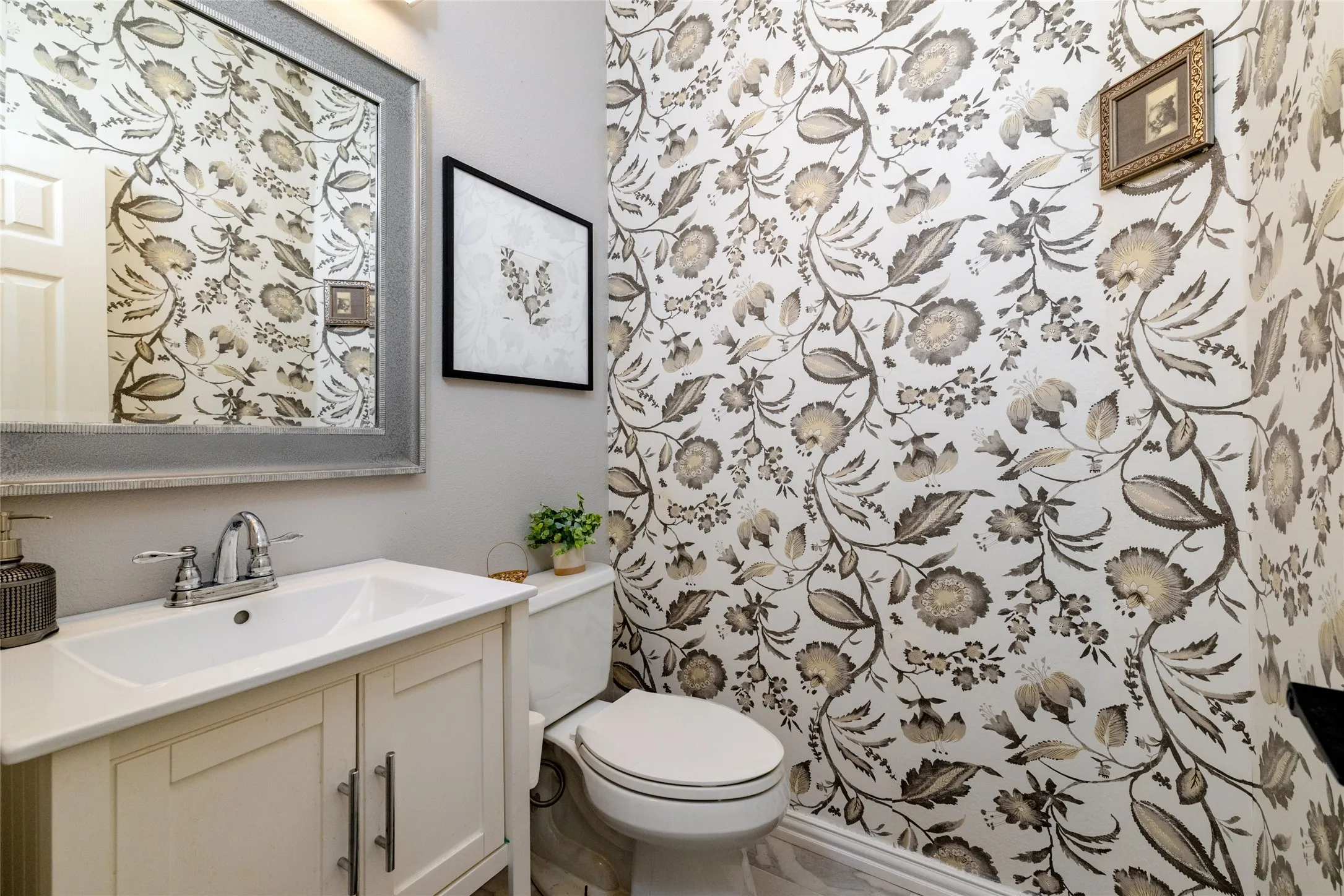 Powder room featuring botanical print wallpaper, a single vanity with storage, a surface-mount sink, and a chrome faucet