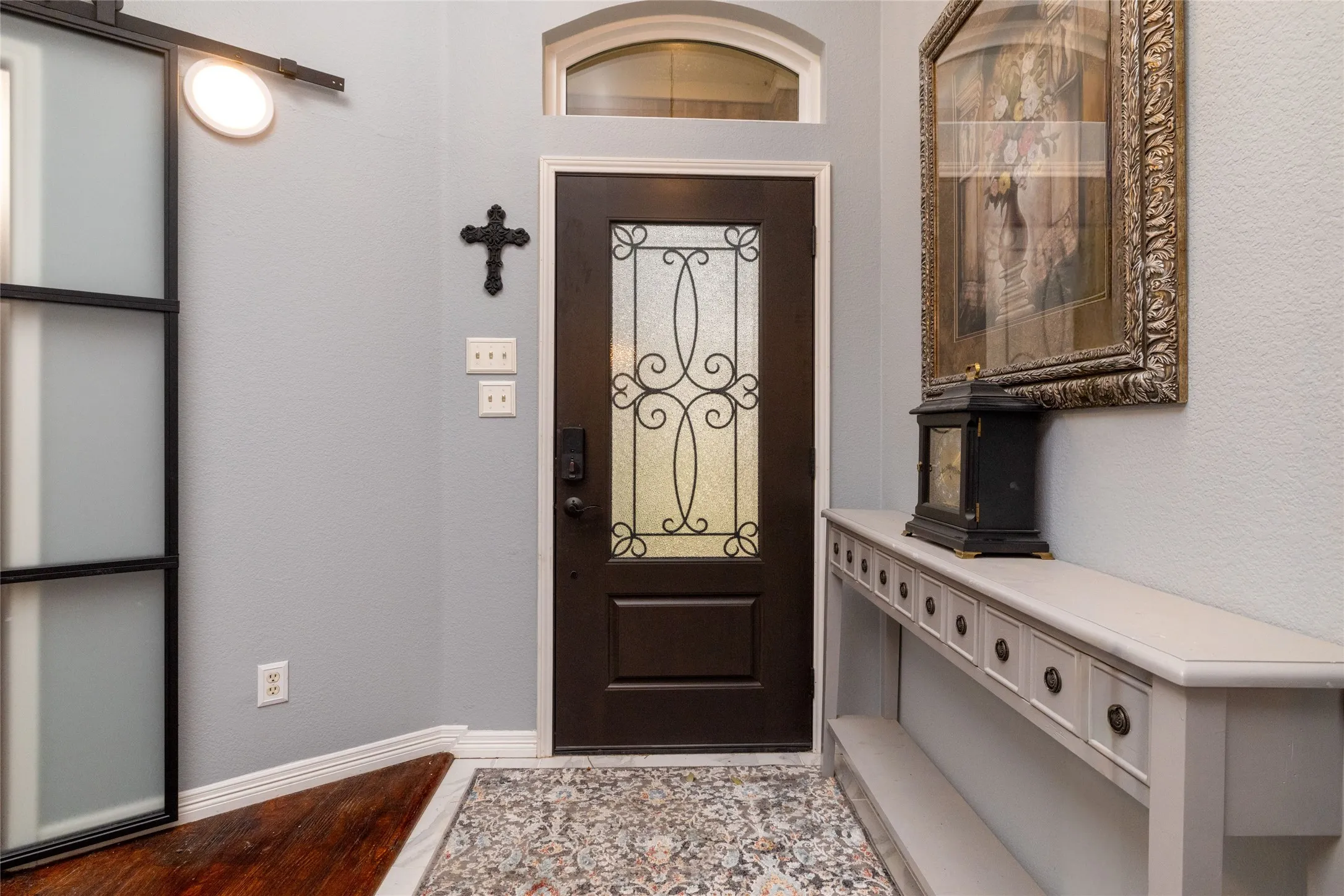 Entryway featuring a dark wood-finish door with decorative glass, an arched transom window, and a frosted glass barn door