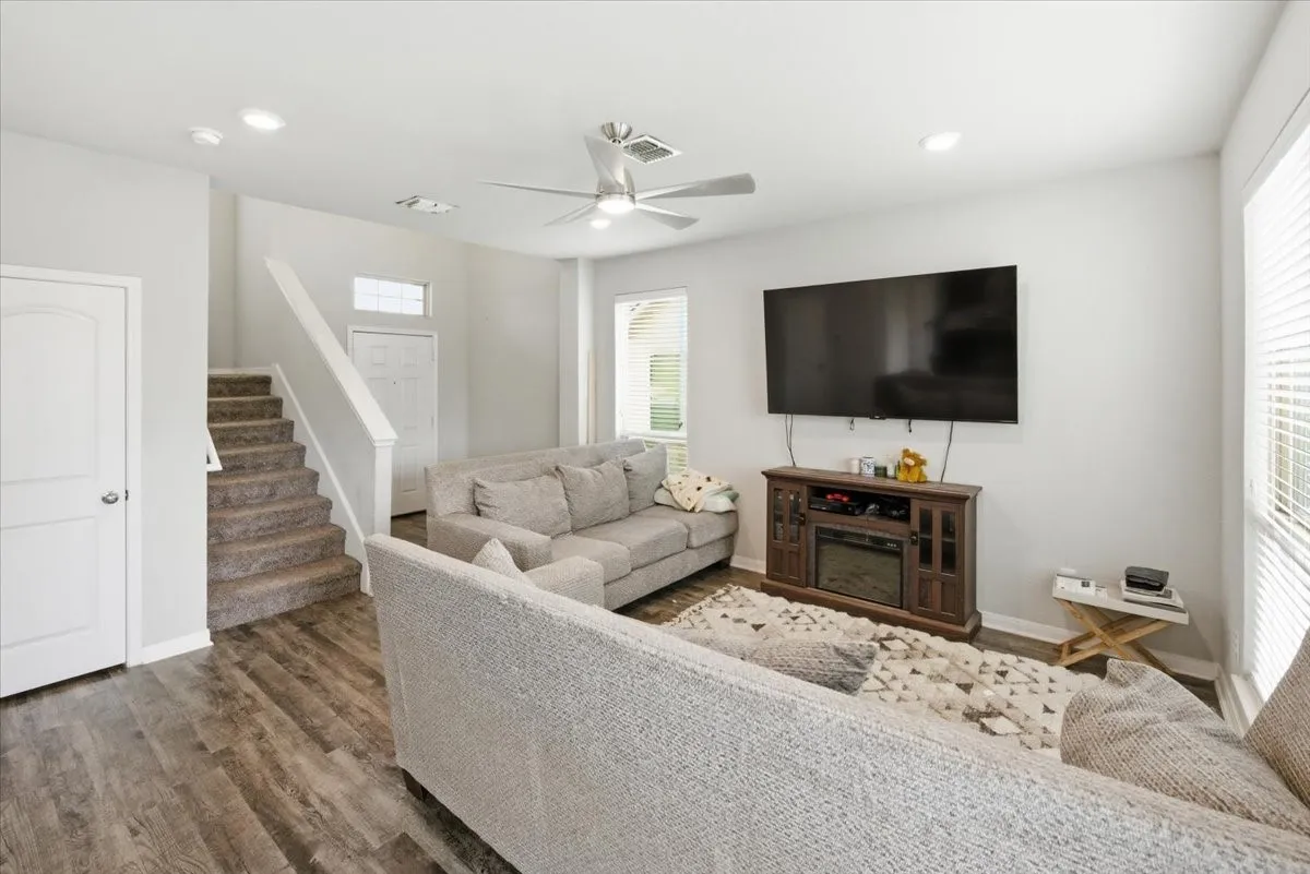 Living room with ceiling fan, wood-look floors, and recessed LED lighting