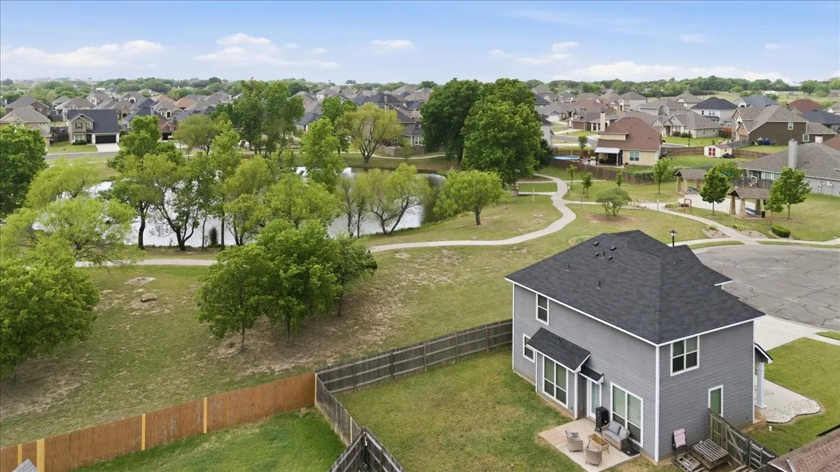 Aerial view showing the home with the neighborhood pond, walking area, and picnic area in the background