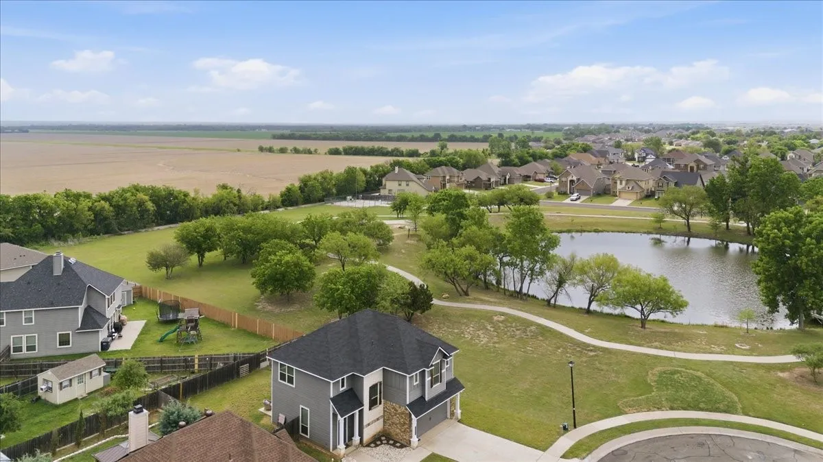 Aerial view featuring a community pond, walking area, and this home in the foreground