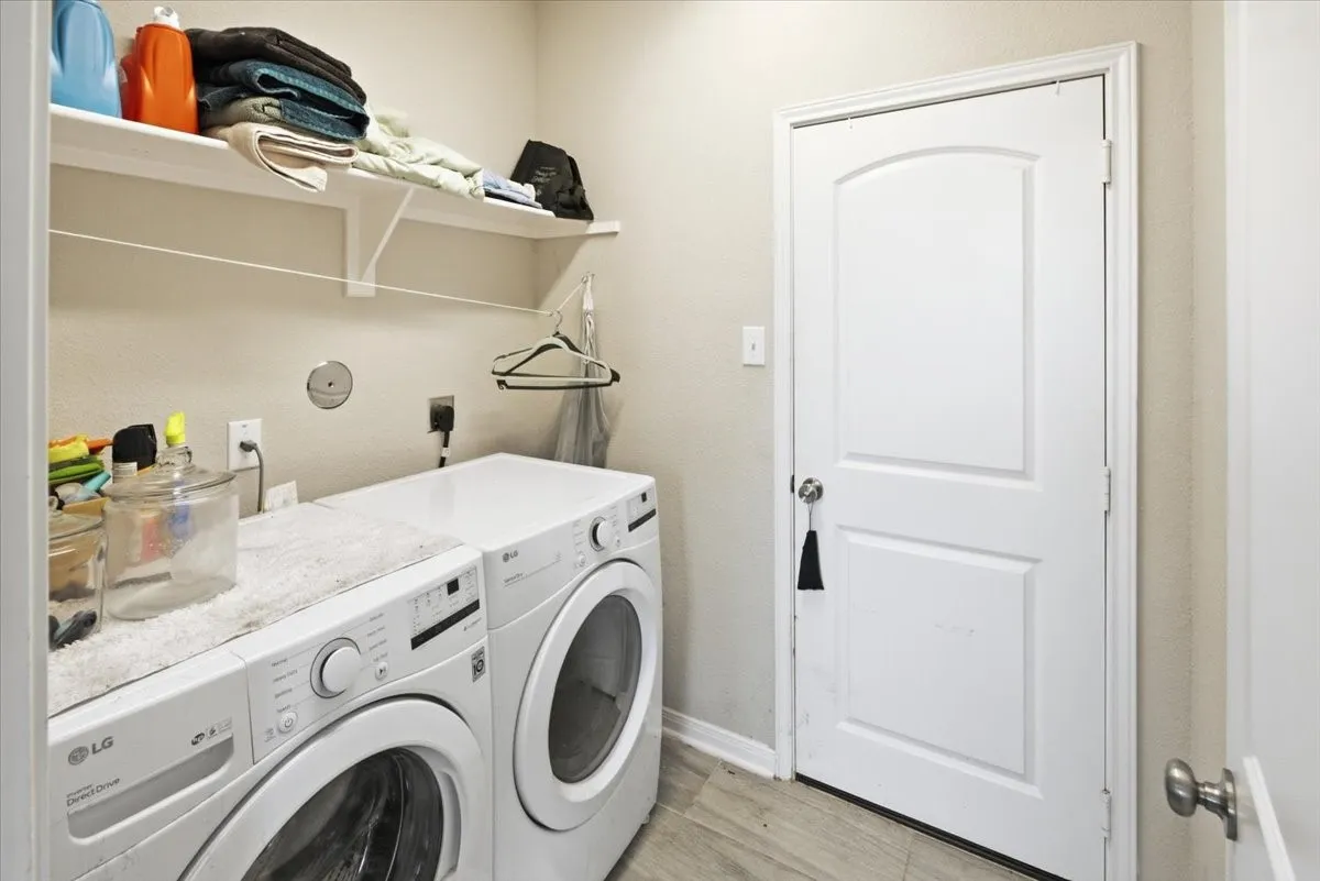Laundry area with washing machine and dryer and light wood-look flooring
