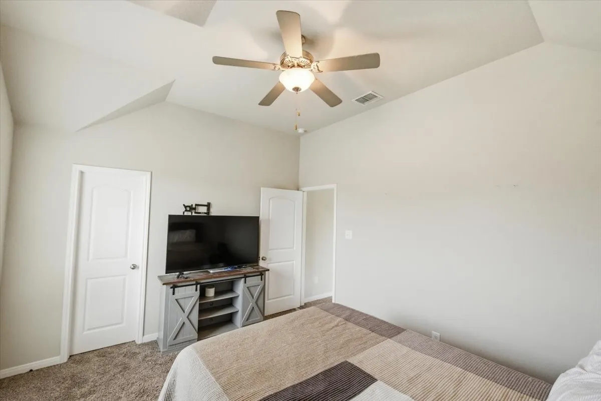 Bedroom featuring vaulted ceiling, carpet flooring, and ceiling fan