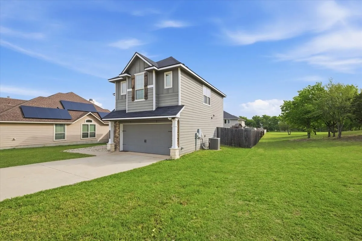 View of property exterior with an attached garage, concrete driveway, and brick, stone, and siding