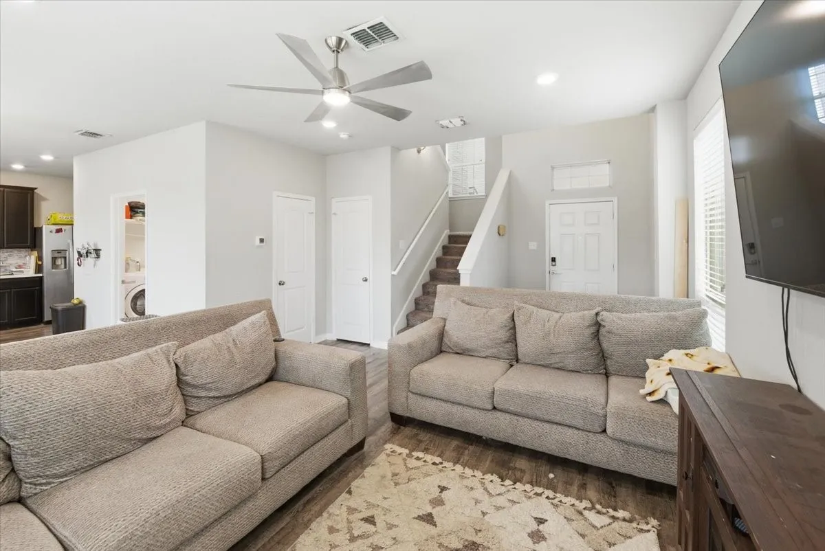 Living room with a ceiling fan, light wood-look flooring, and recessed LED lighting