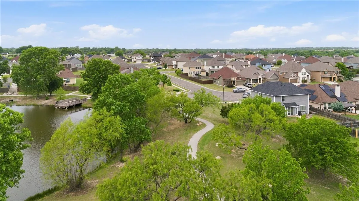 Aerial view of neighborhood pond, walking area, and this home on the right