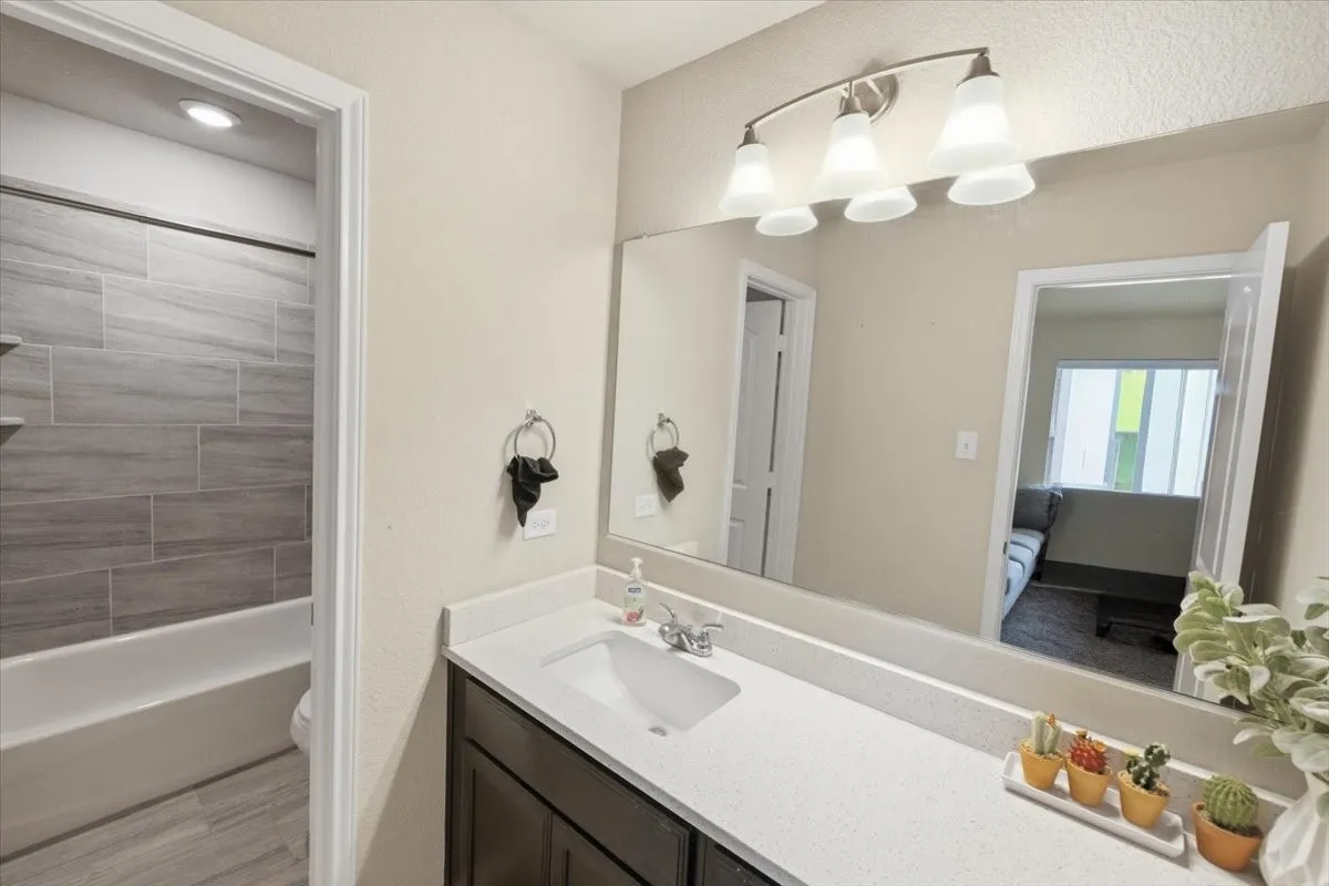 Bathroom featuring vanity, bathtub / shower combination, and decorative lighting