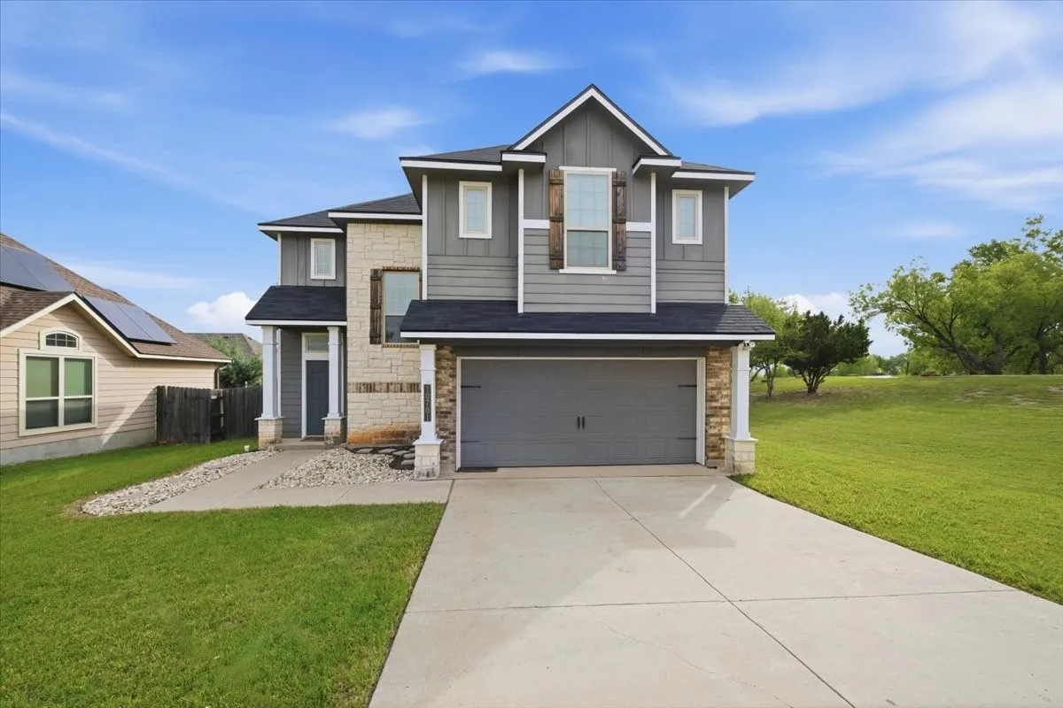 View of front of home with 2-car garage, featuring stone, brick and siding, and concrete driveway