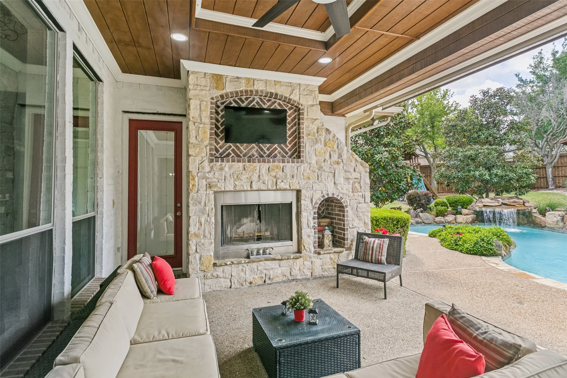 Covered Patio with Brick Fireplace and Entertainment with secondary access to Primary Bedroom