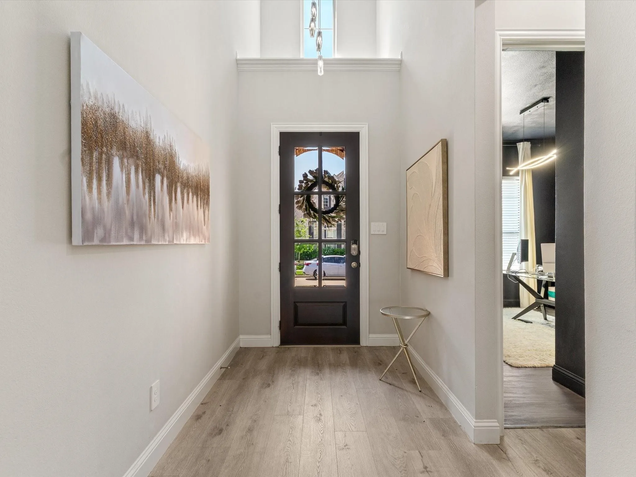 Entry foyer featuring wood-finish flooring, high ceilings, a dark-paneled front door with glass inserts, and a transom window above