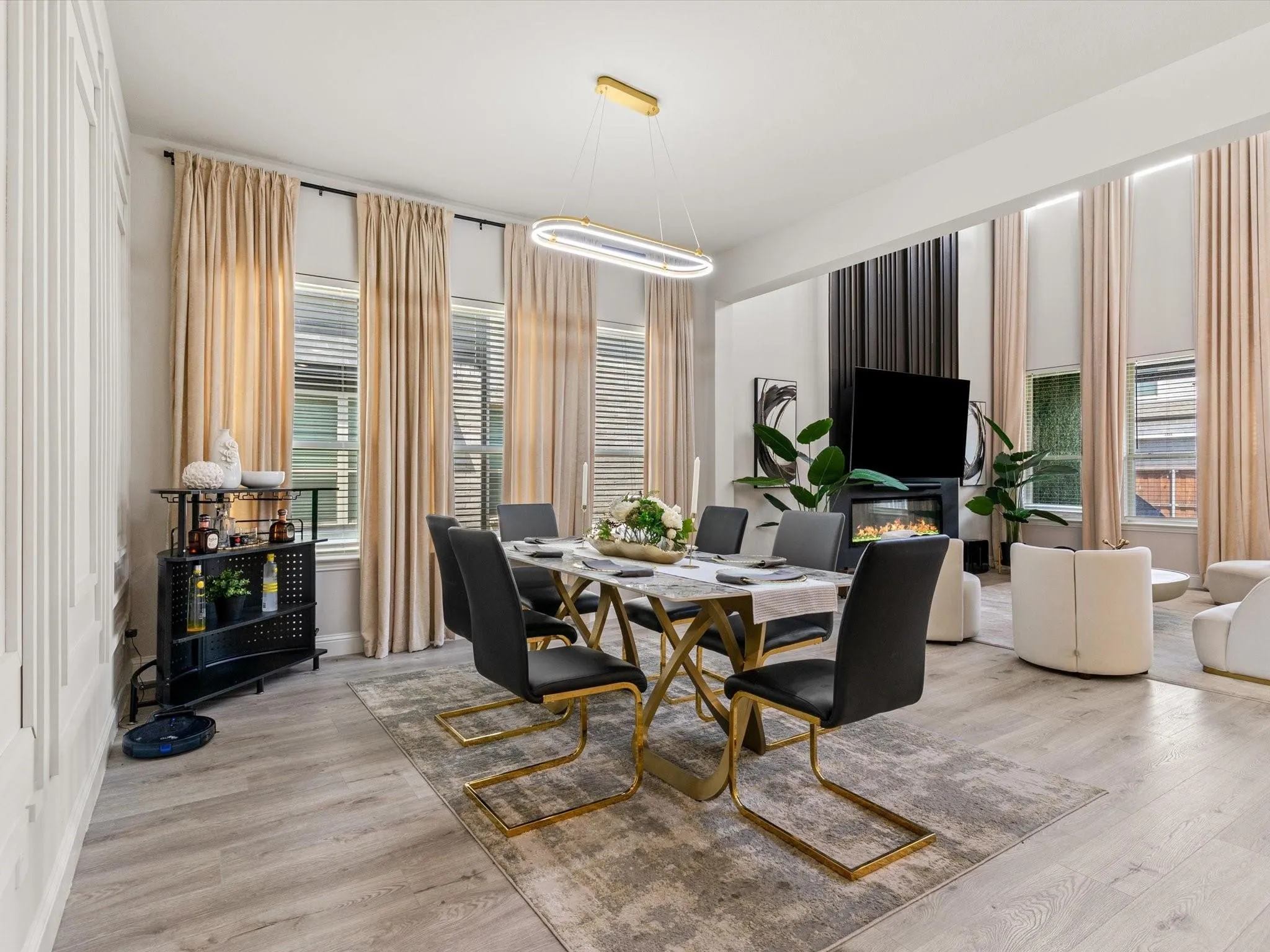 Spacious dining area featuring wood-finish flooring, an elongated ceiling light fixture, and multiple windows with blinds