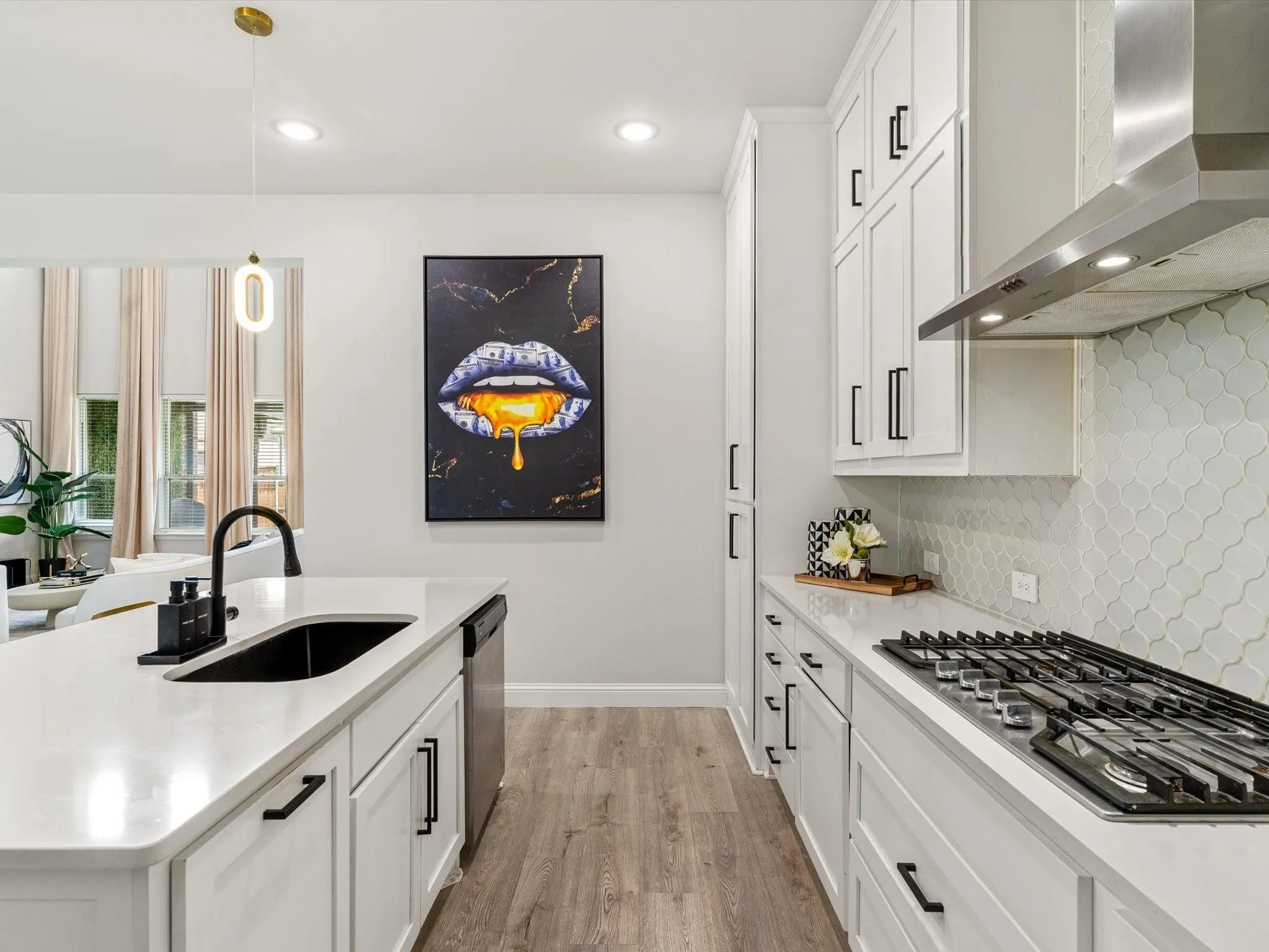 Contemporary kitchen featuring white cabinetry, light-colored countertops, a gas cooktop with a stainless steel range hood, a black sink with a matte black faucet, and wood-finish flooring