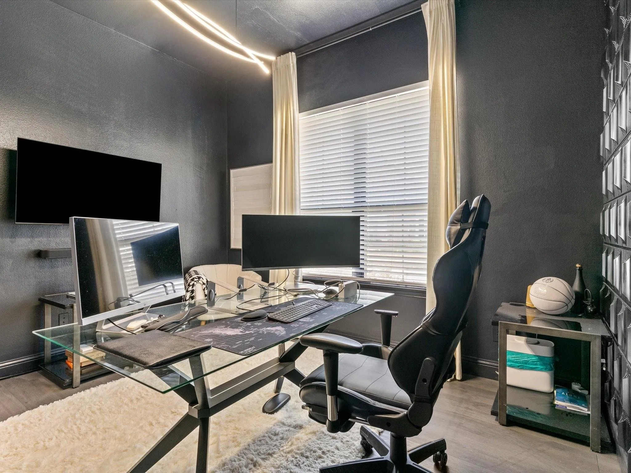 Dedicated space featuring dark-toned walls, wood-finish flooring, and a large window with blinds and curtains