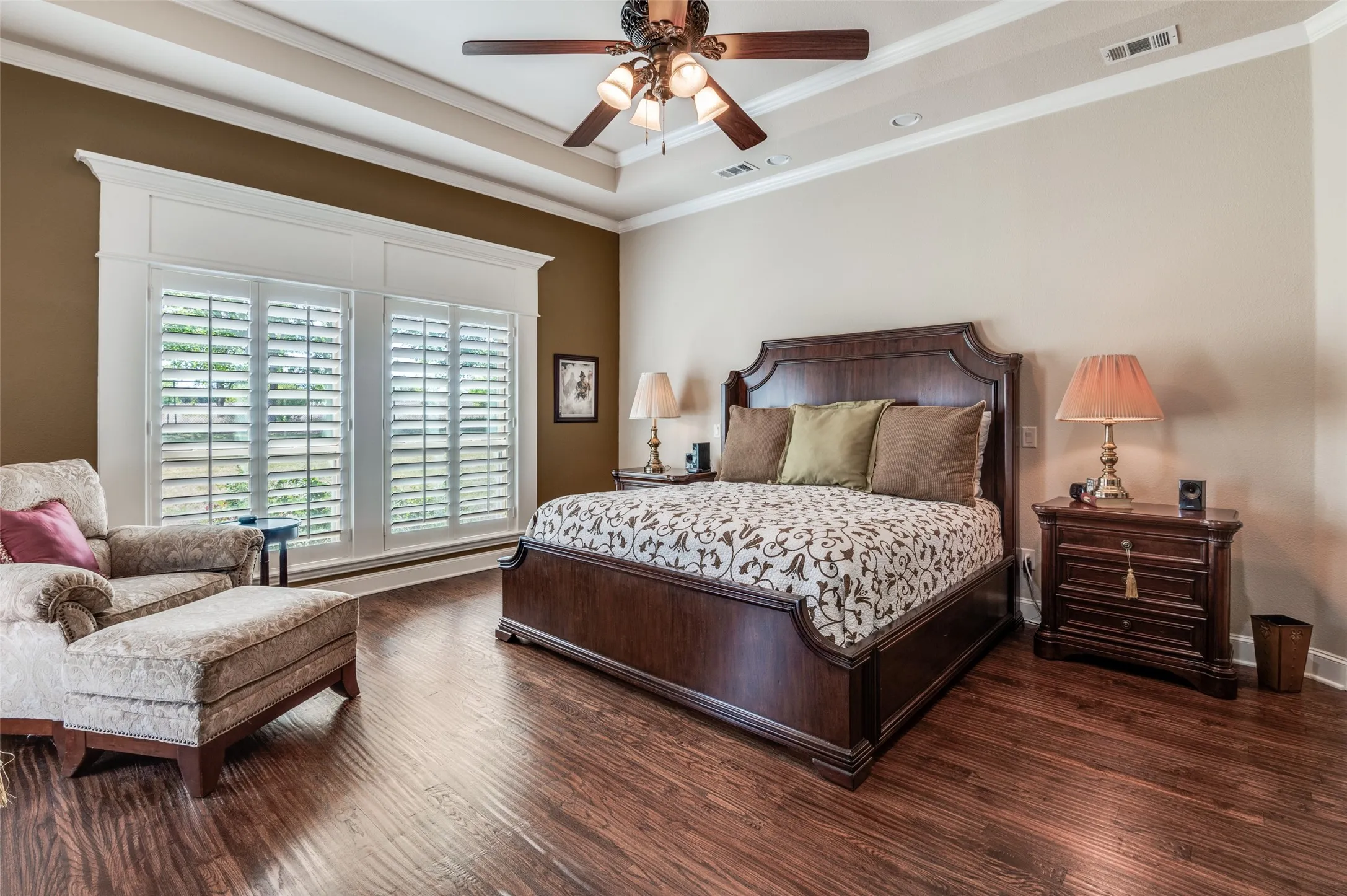 This primary suite features hand scraped hardwoods, custom plantation shutters and window trim, crown molding, door to patio.