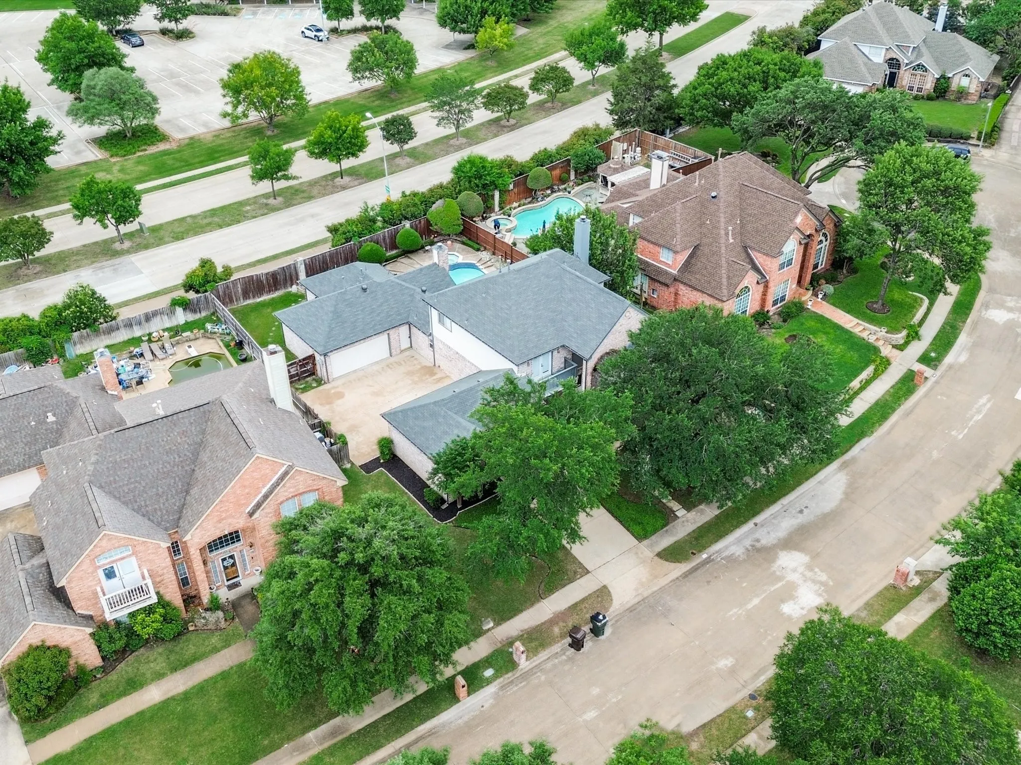 Aerial perspective showcasing a residential property with a private swimming pool, extensive patio space, and mature landscaping
