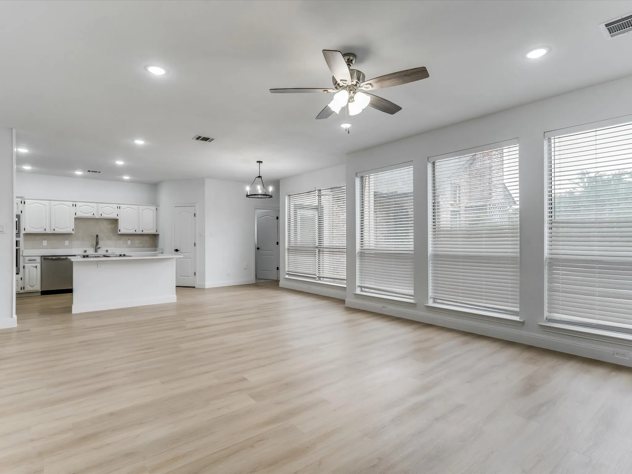Open-concept living area featuring light wood-finish flooring, recessed lighting, and a contemporary ceiling fan