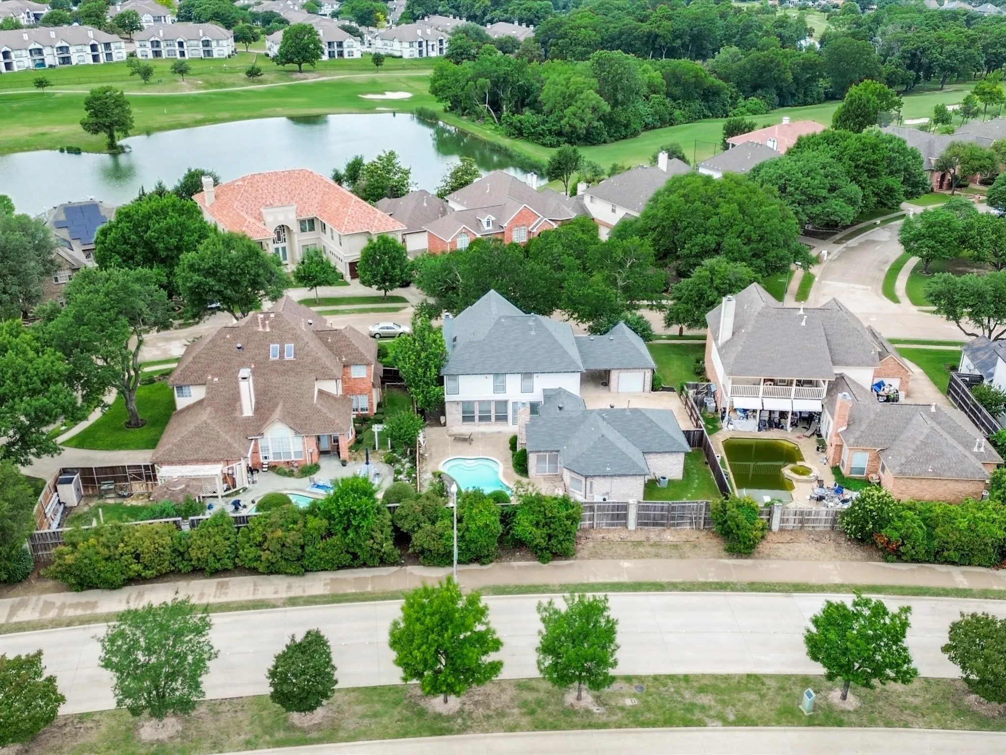 Expansive backyard featuring an inground swimming pool, surrounding patio space, and mature perimeter landscaping