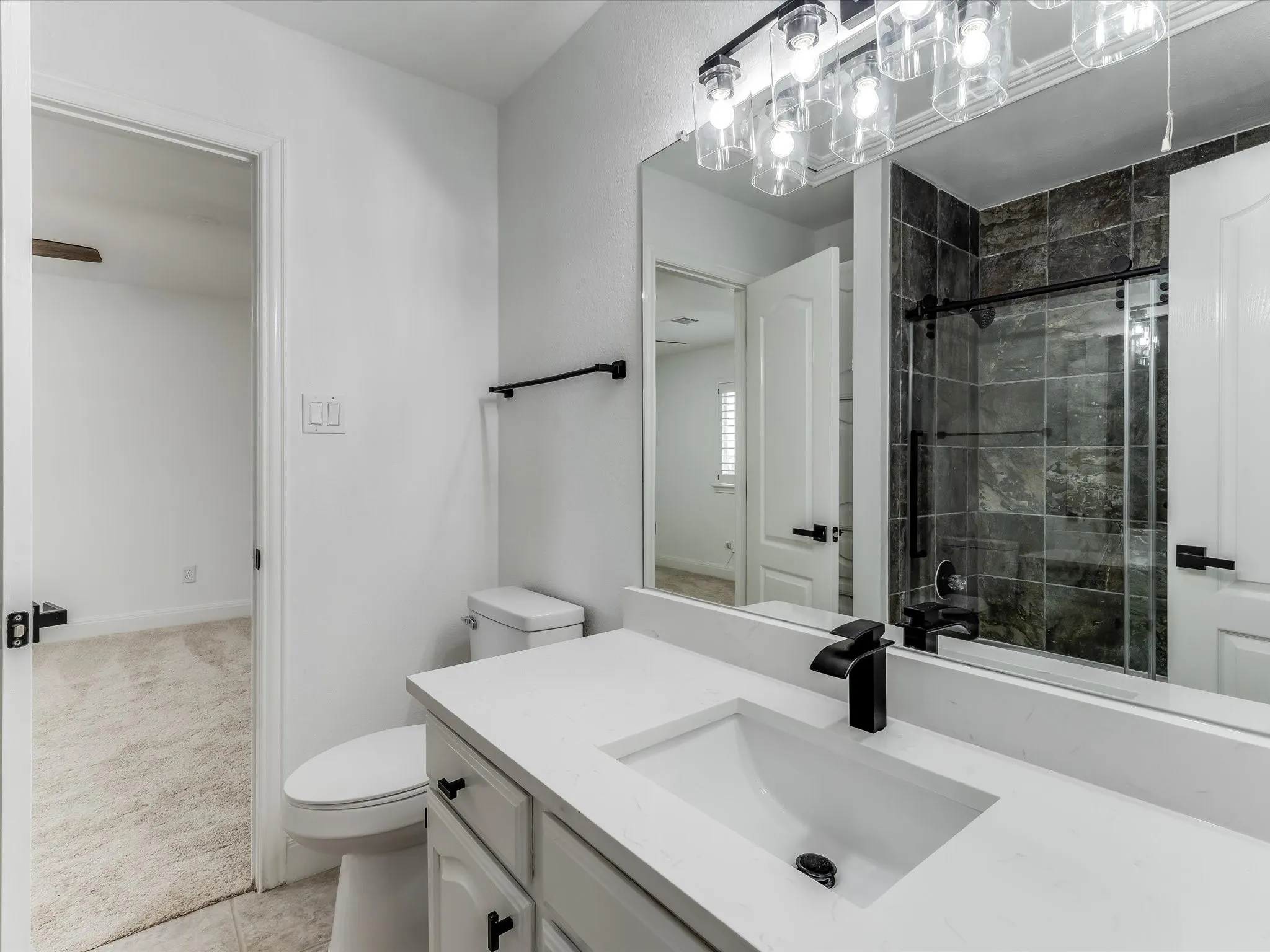 Bathroom featuring a white vanity with a rectangular undermount sink, a matte black faucet, and a large framed mirror