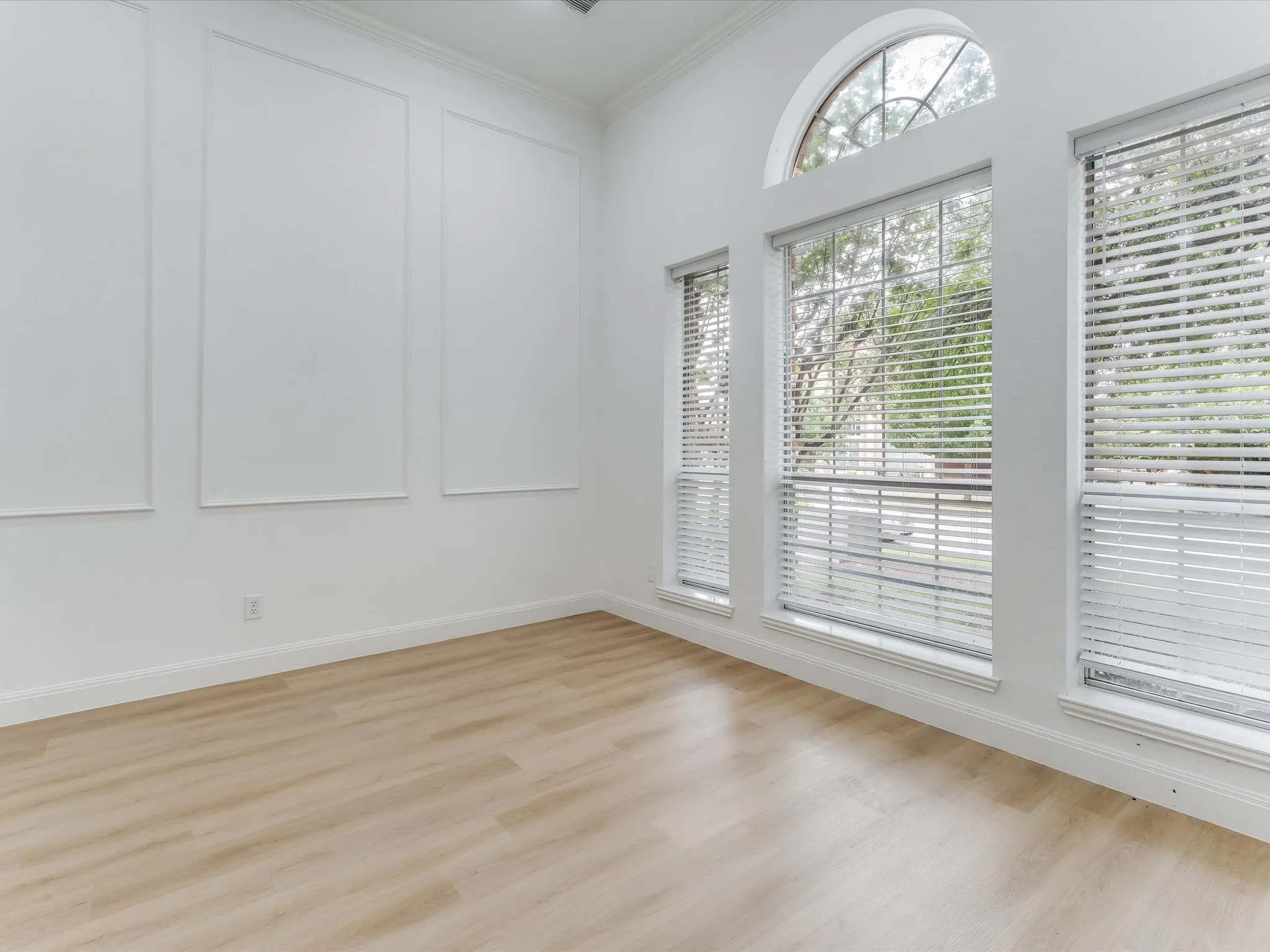 Room featuring high ceilings, wood-finish flooring, and white baseboards