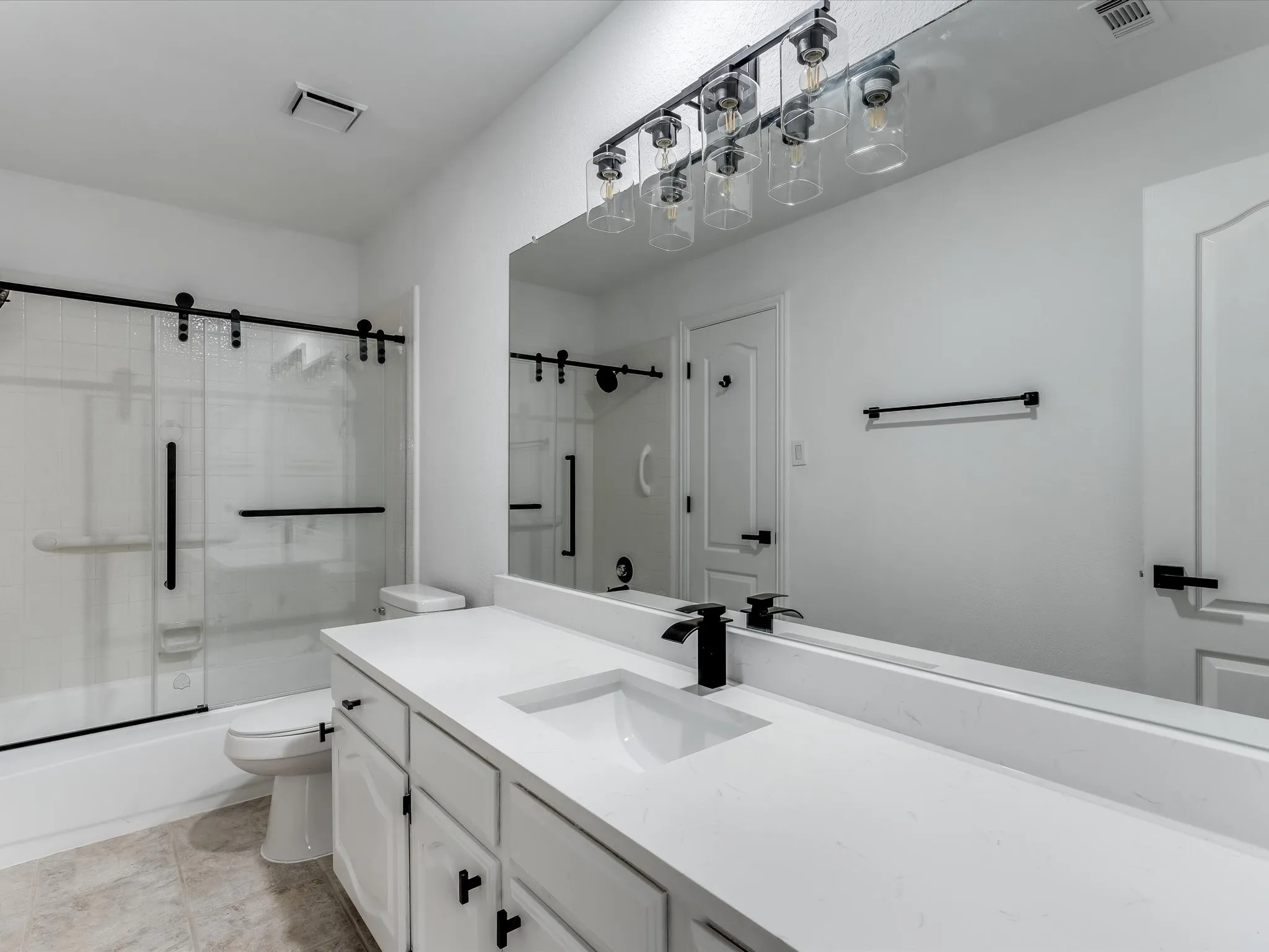 White vanity with an integrated sink, black matte faucet, and matching black hardware