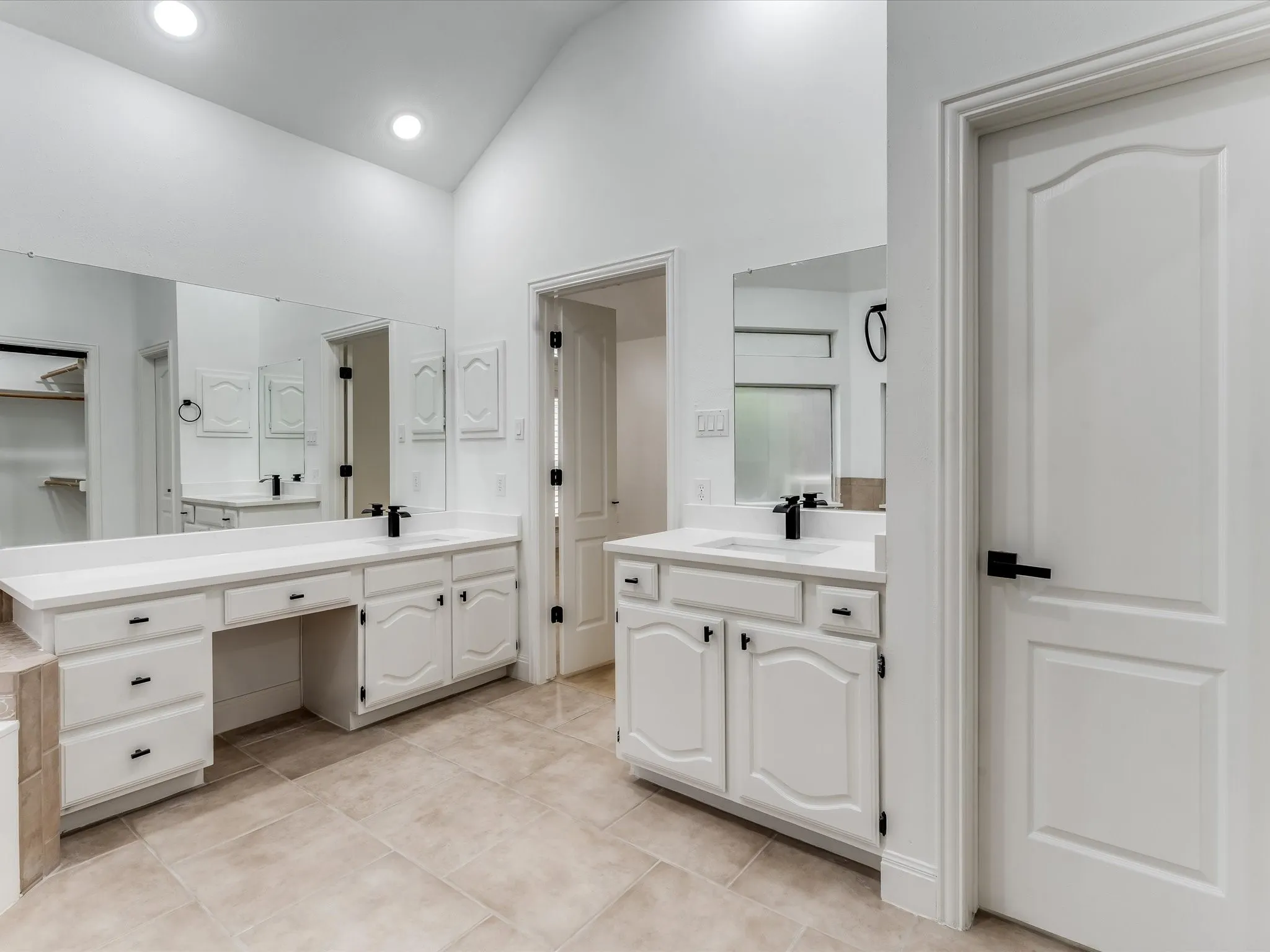 White vaulted ceilings featuring recessed lighting, a dual vanity with white cabinetry, white countertops, and black fixtures