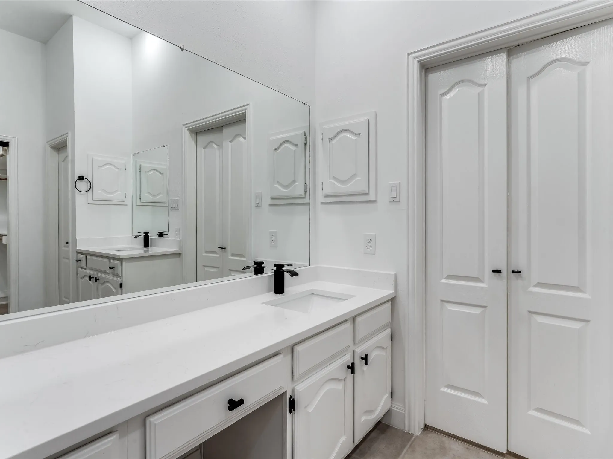 Vanity area featuring a continuous countertop with integrated sinks and matte black​​‌​​​​‌​​‌‌​‌‌​​​‌‌​‌​‌​‌​​​‌​​ fixtures
