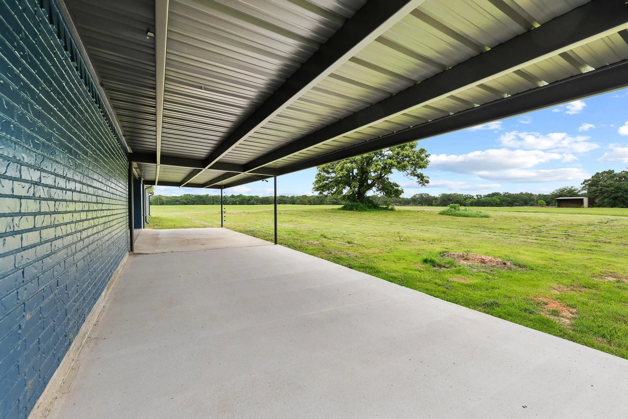 Covered patio with a painted brick wall and a corrugated metal roof