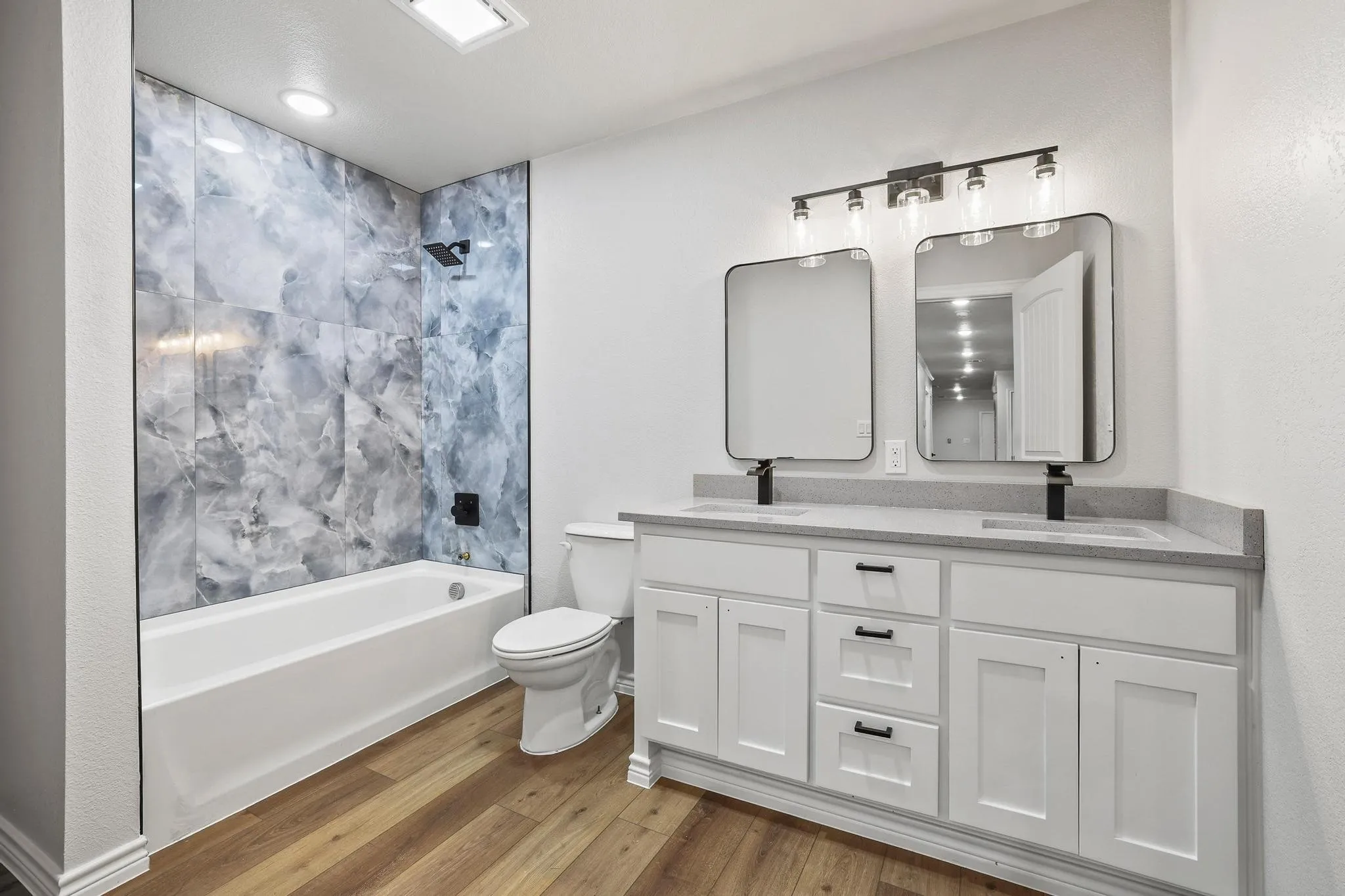 Bathroom featuring a dual vanity with a light-colored countertop, white cabinetry with black hardware, and two rectangular framed mirrors