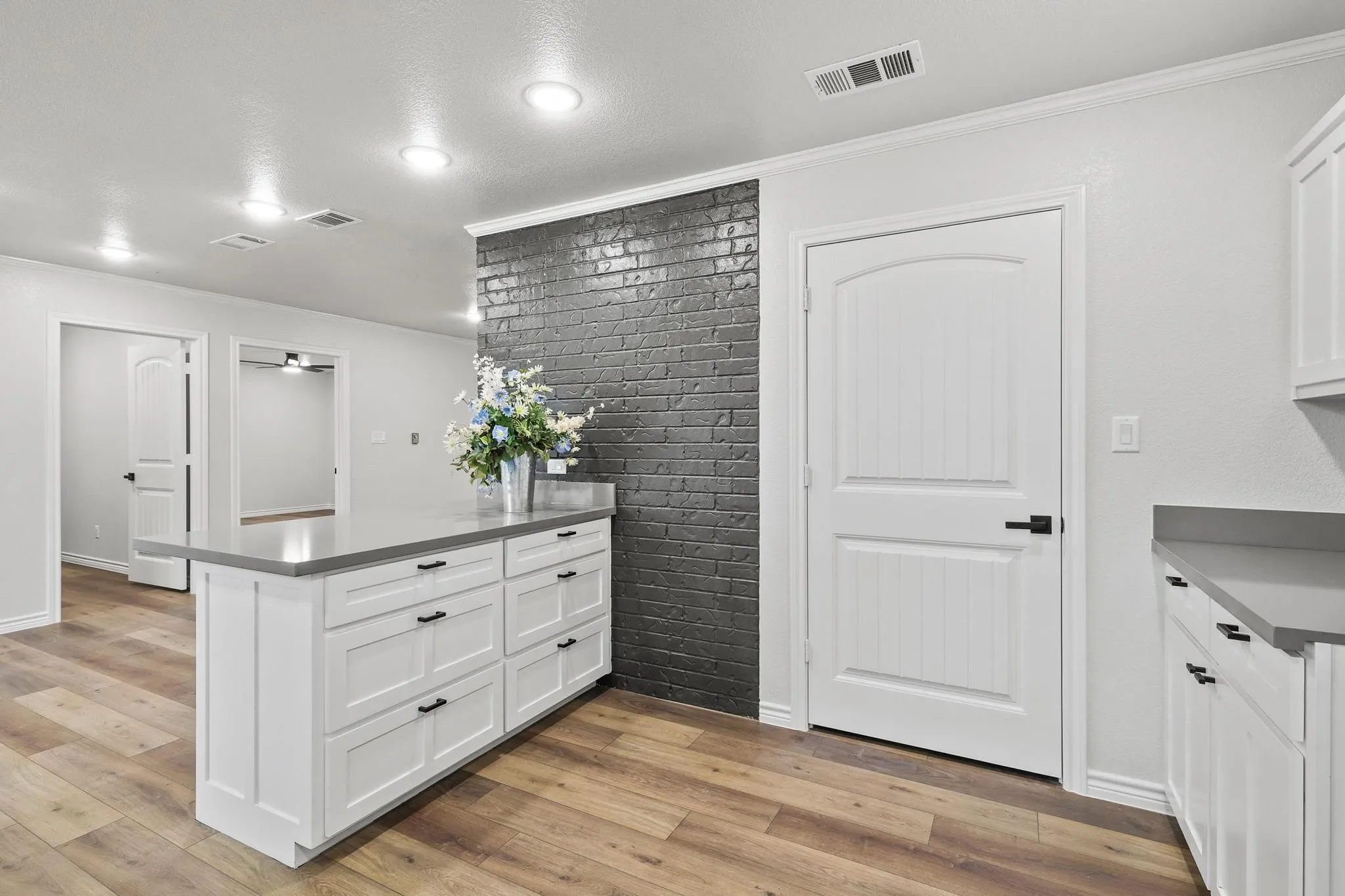 Kitchen island featuring white Shaker-style cabinetry, a solid surface countertop, and matte black hardware