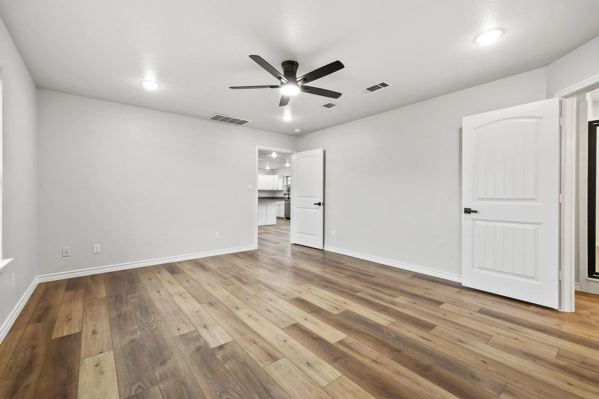 Spacious room featuring wood-finish flooring, light gray walls, and recessed lighting