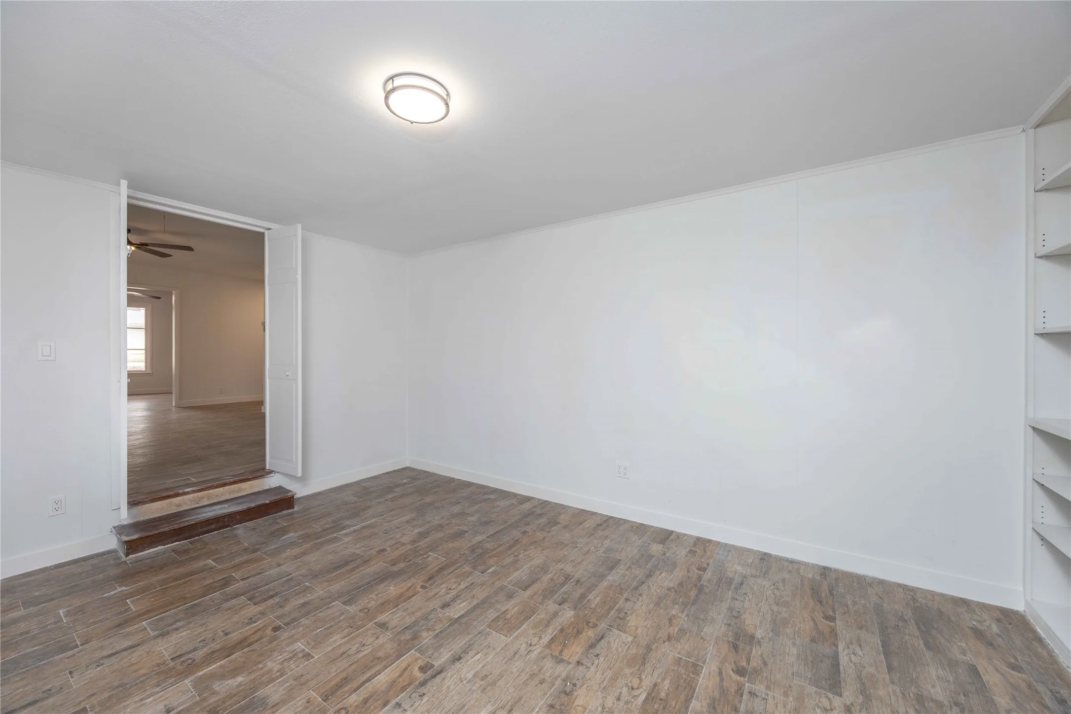 Expansive room featuring wood-finish flooring and a built-in shelving unit