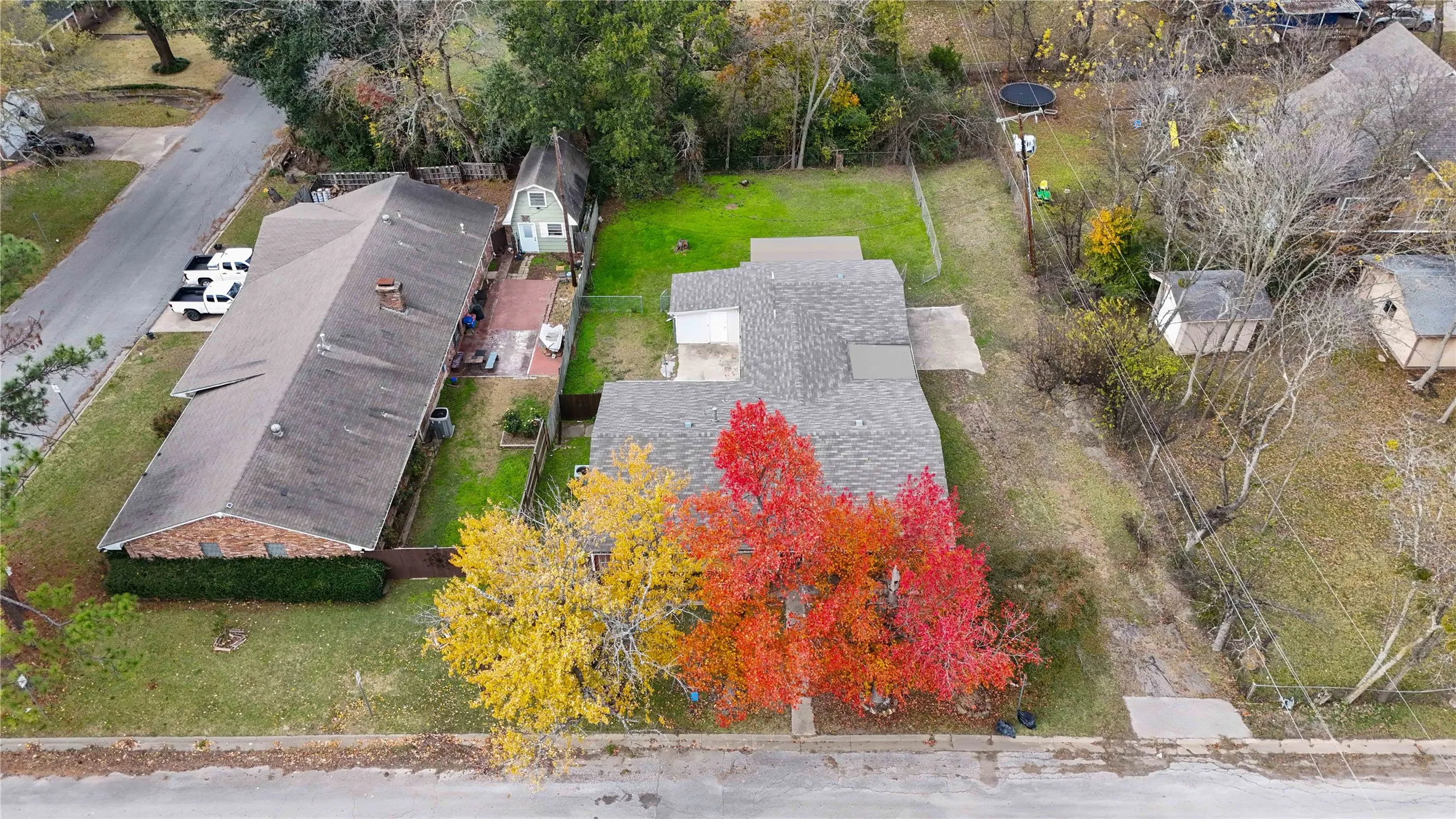 Expansive property featuring a gabled roofline, mature trees with vibrant fall foliage, and a paved driveway