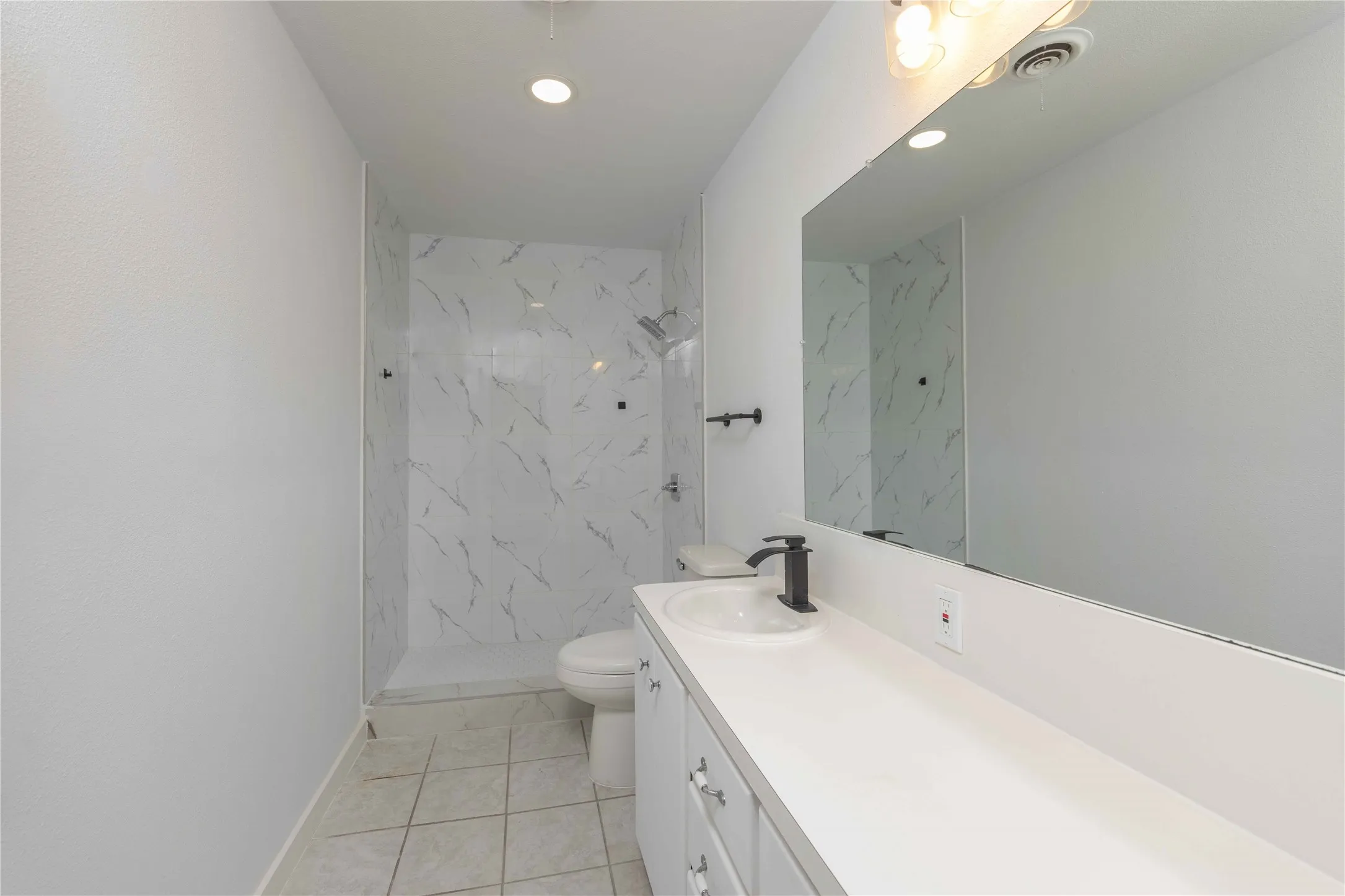 Full bathroom featuring a white vanity with integrated sink, matte black faucet, and a large wall-mounted mirror
