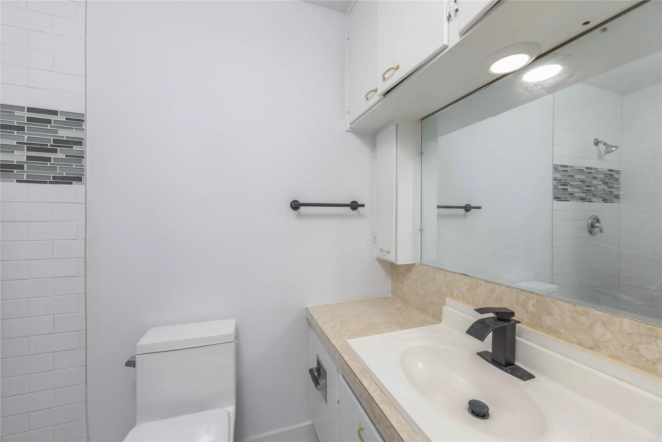 Bathroom featuring a vanity with an integrated sink, a dark bronze faucet, and a large wall-mounted mirror